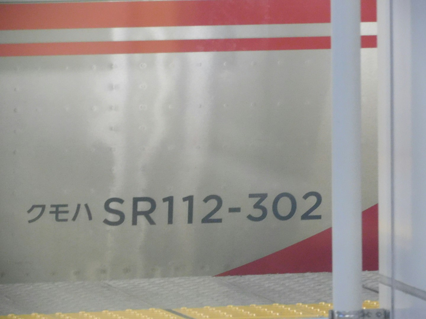 壁に沿う廊下の部屋番号「SR112-302」表示のある区画
