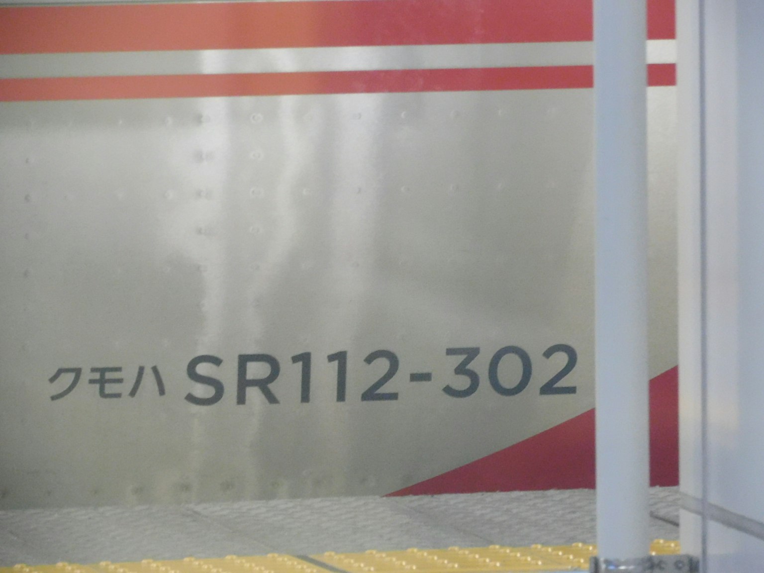 Treno argentato con il numero SR112-302 e strisce rosse
