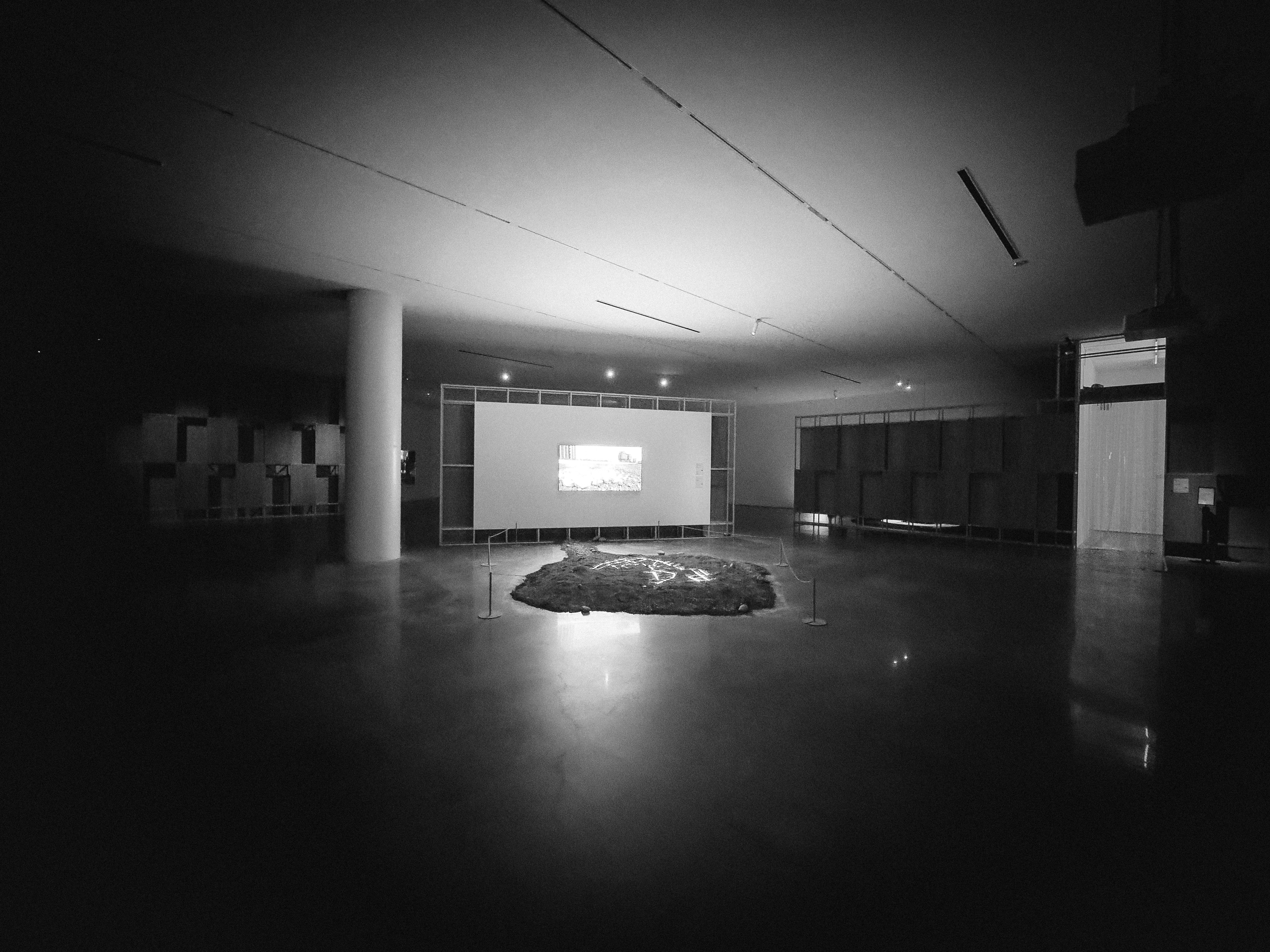暗い屋内展示空間の床に広がる光と影の演出