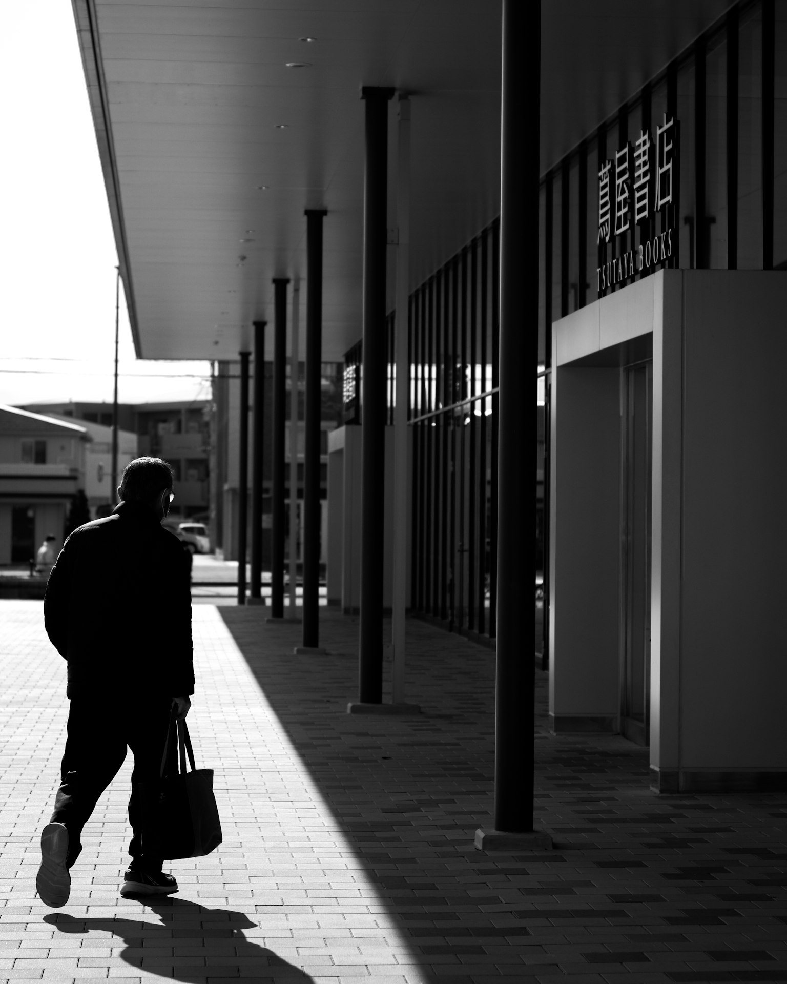Silhouette d'une personne marchant le long d'un bâtiment moderne en noir et blanc