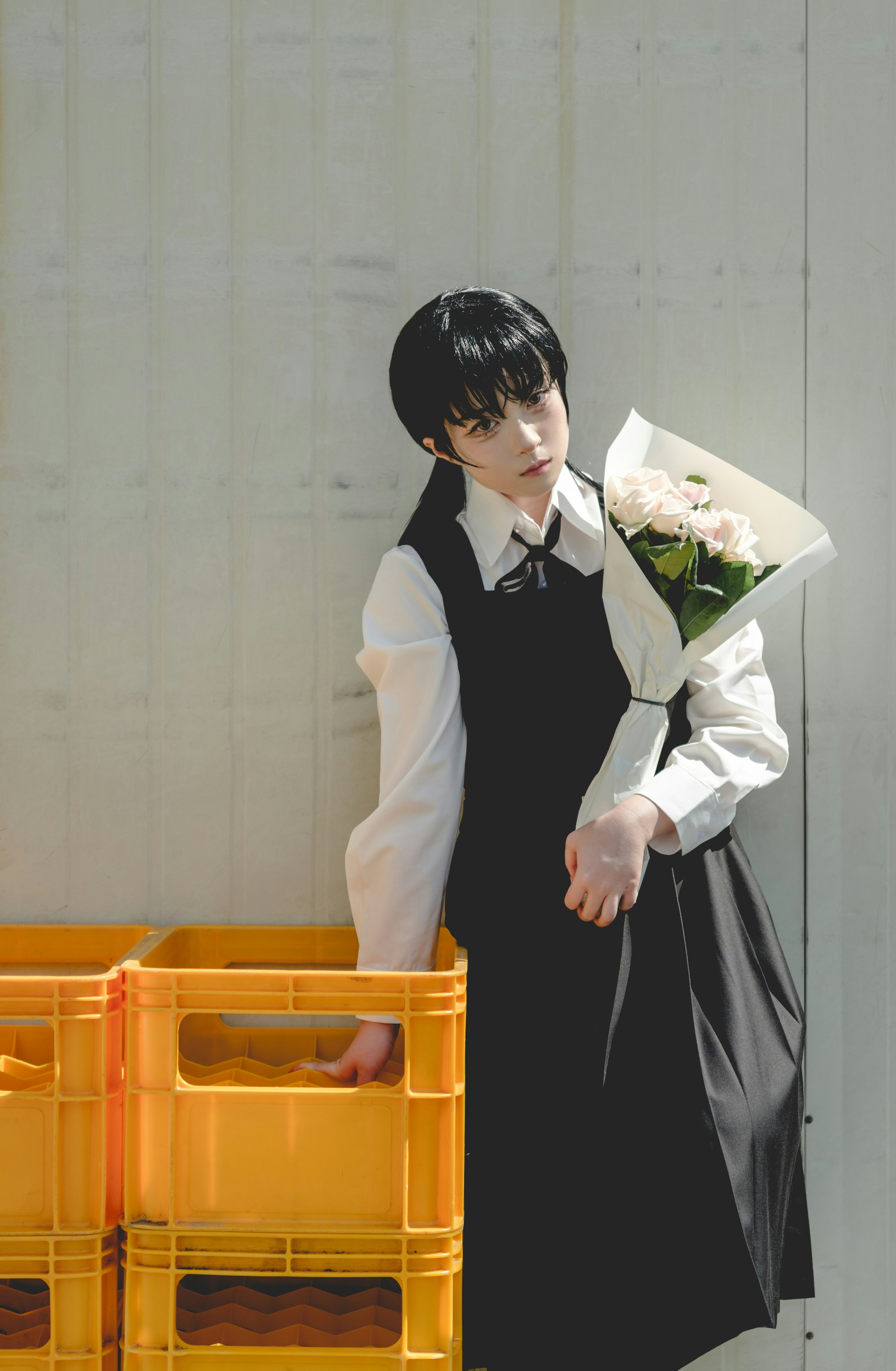 壁際で花束を持つ制服風の人物