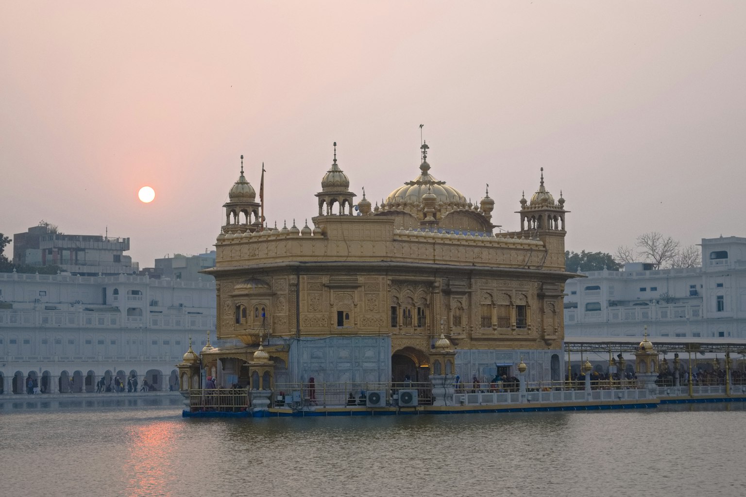 Goldener Tempel mit ruhigem Wasserreflexion bei Sonnenuntergang