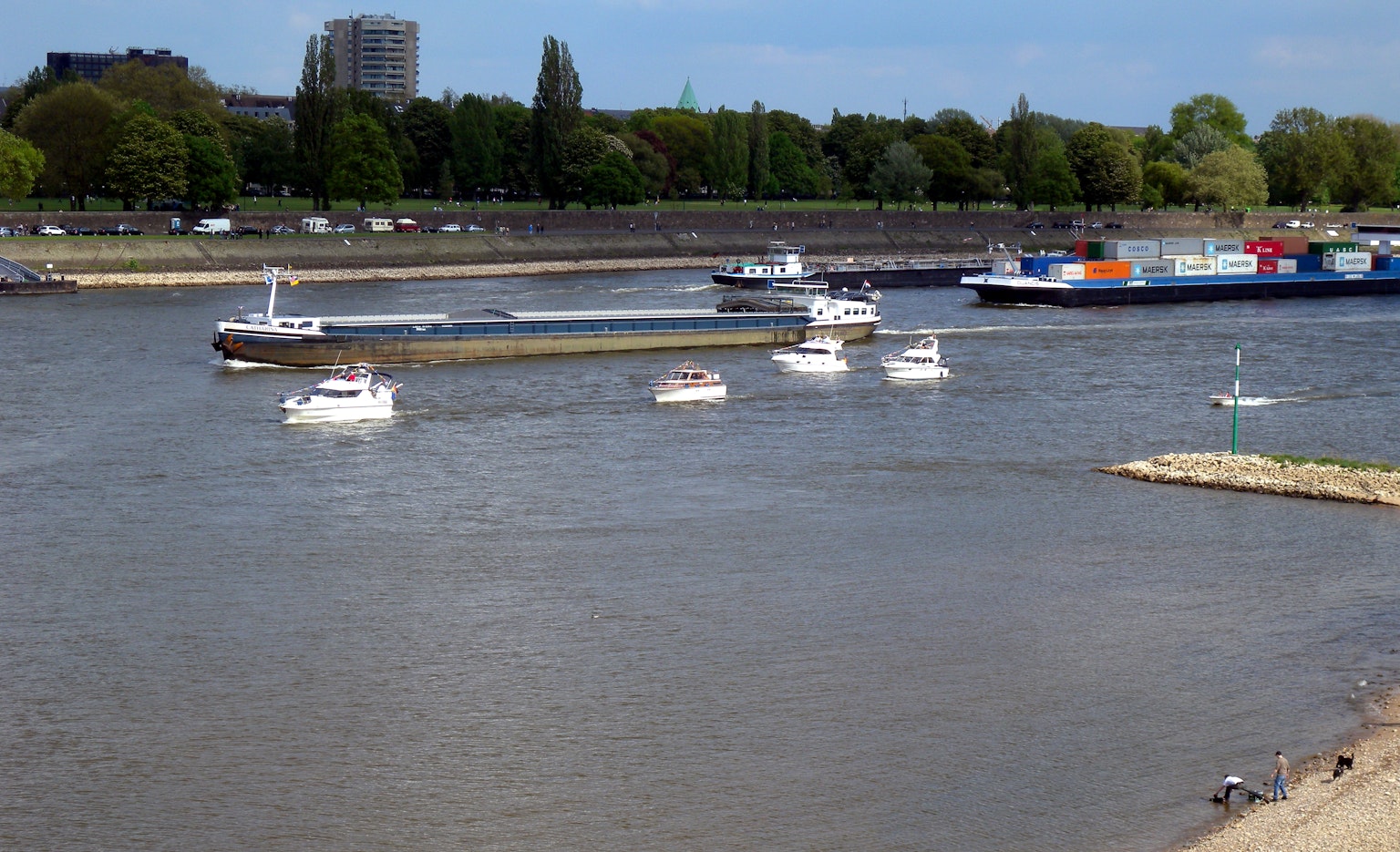 Vista de pequeños barcos y un barco de carga navegando por el río