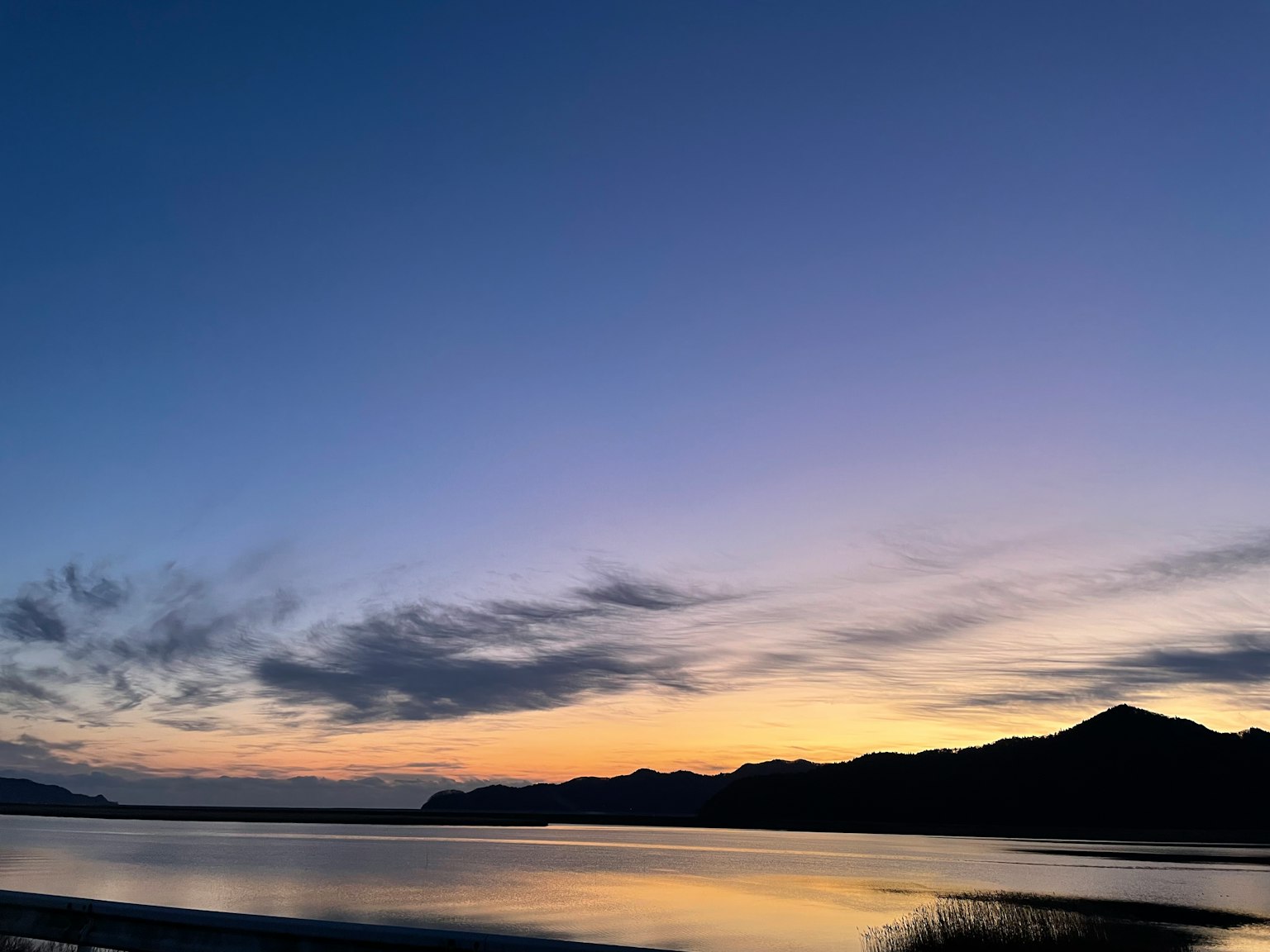 Schöner Sonnenuntergang über einem See mit Bergen im Hintergrund