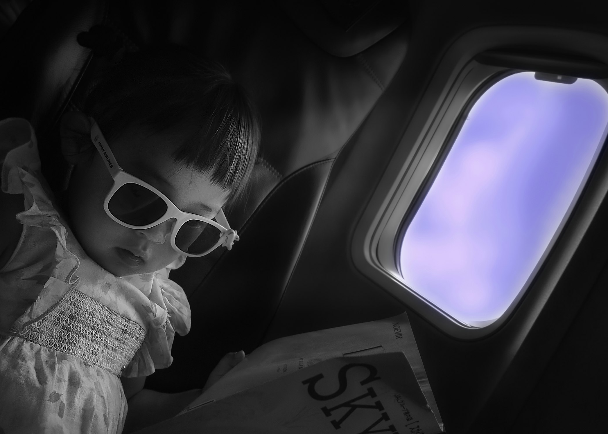 飛行機の機内で窓の外を見つめる子ども