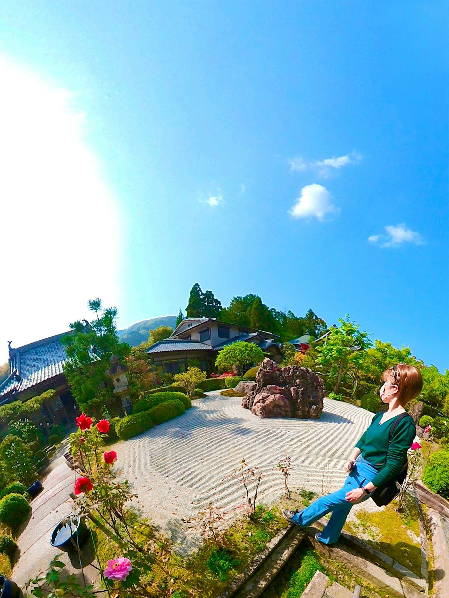 Une femme assise dans un beau jardin avec ciel bleu et verdure luxuriante