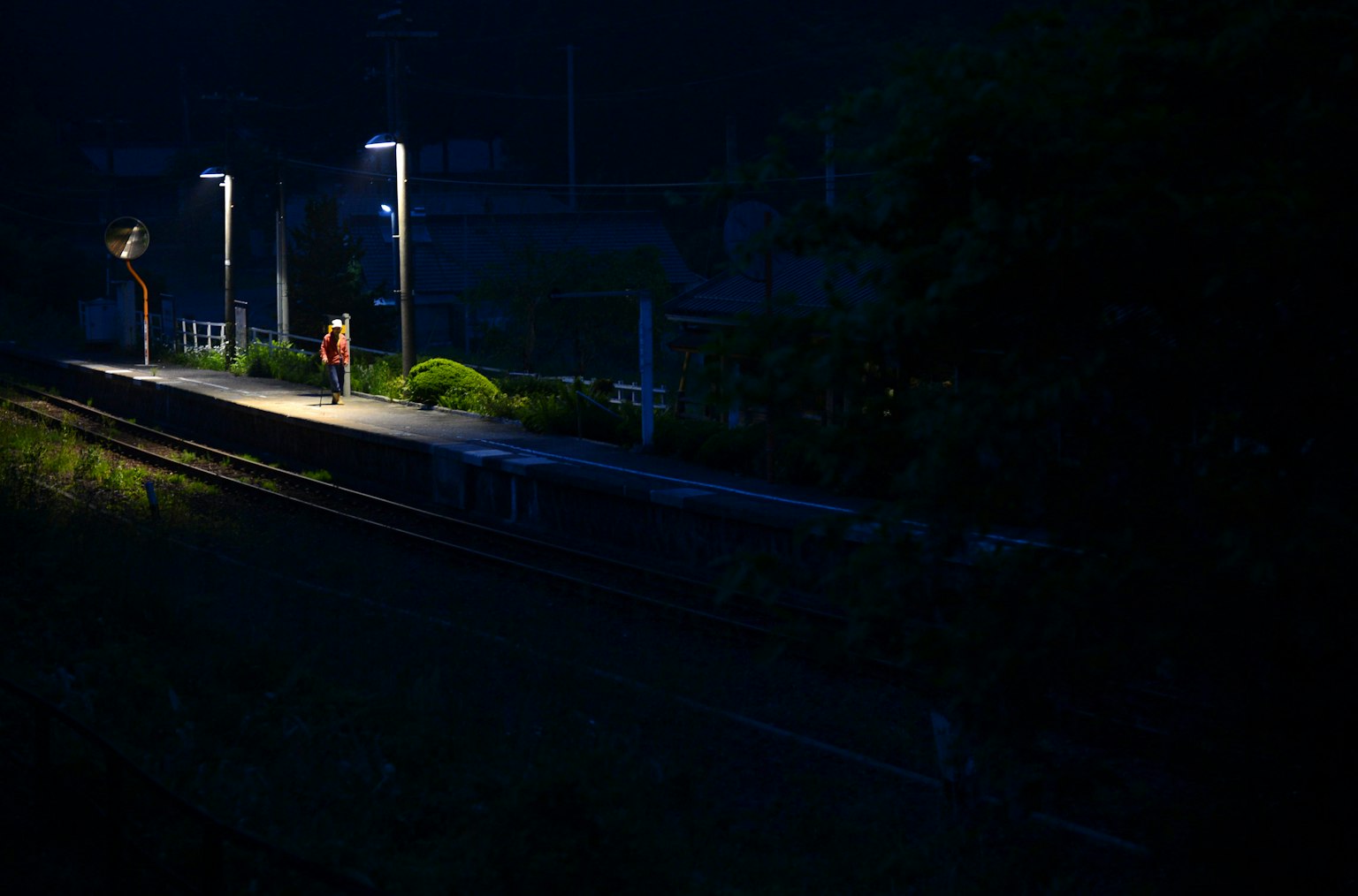Persona in piedi su una piattaforma ferroviaria buia con luci