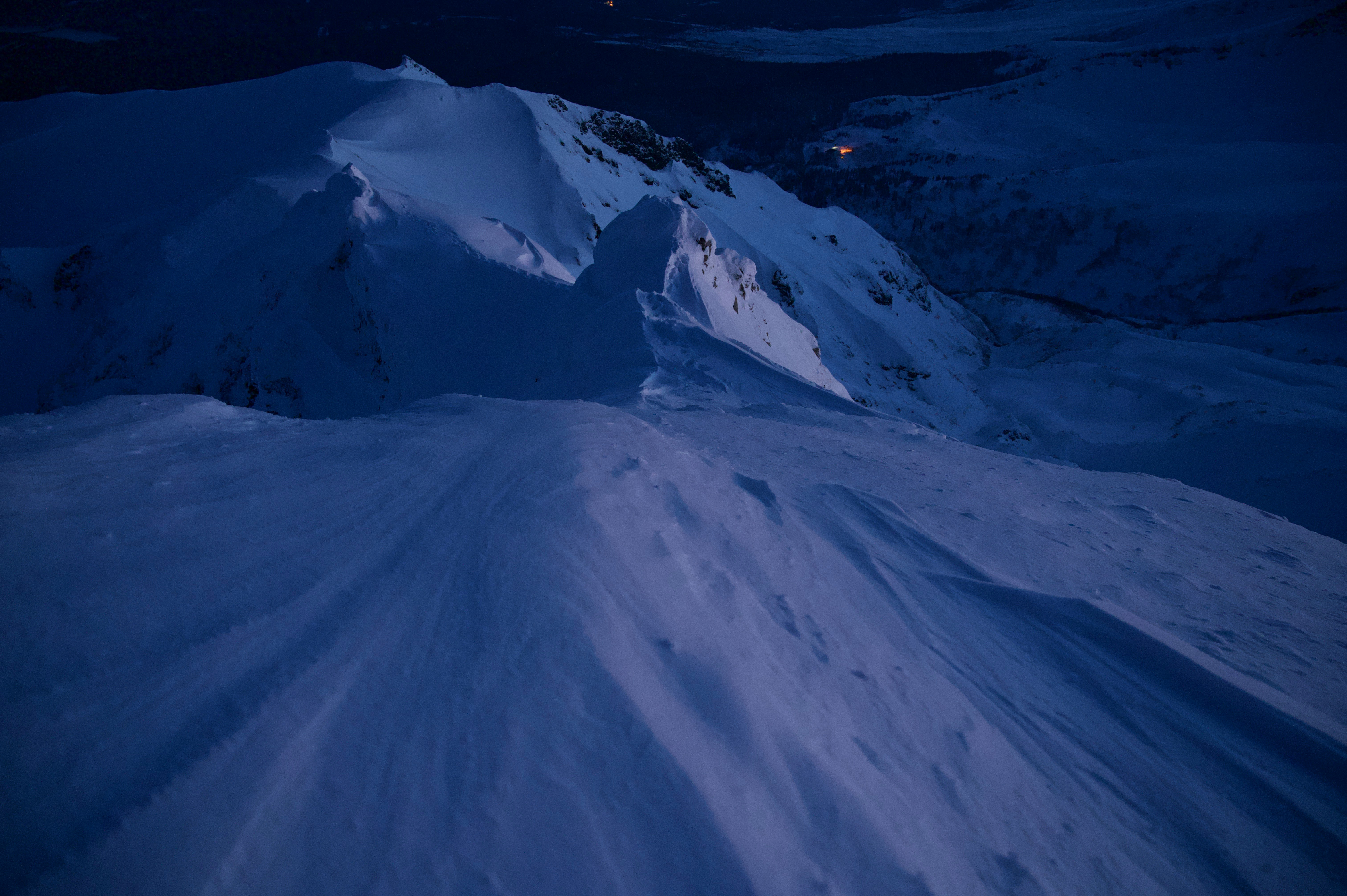 夜の雪山を滑るように伸びるスキーコースの斜面