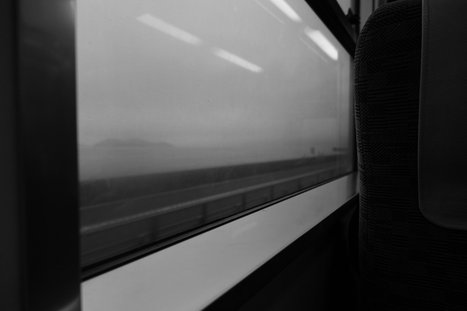 Black and white view from a train window showing a blurred landscape