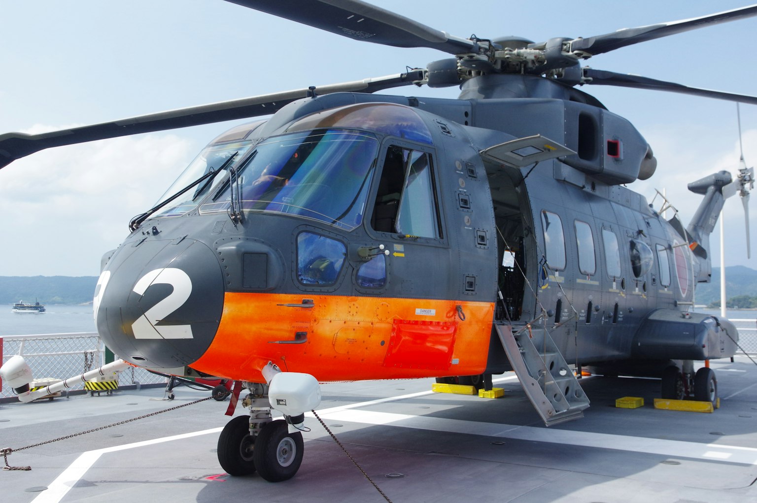 Military helicopter with orange markings and a view of the sea in the background