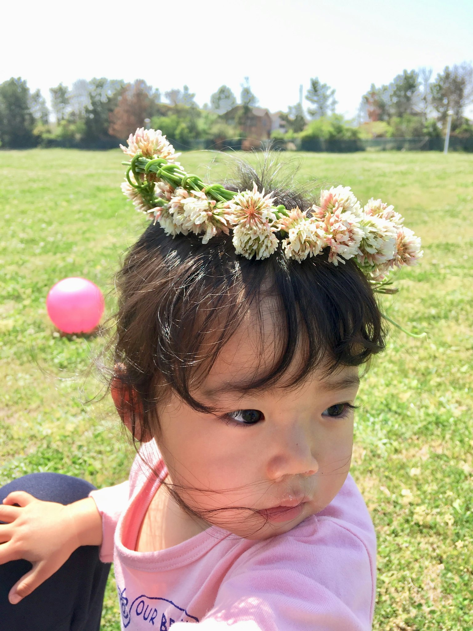 Niña con una corona de flores jugando en un parque