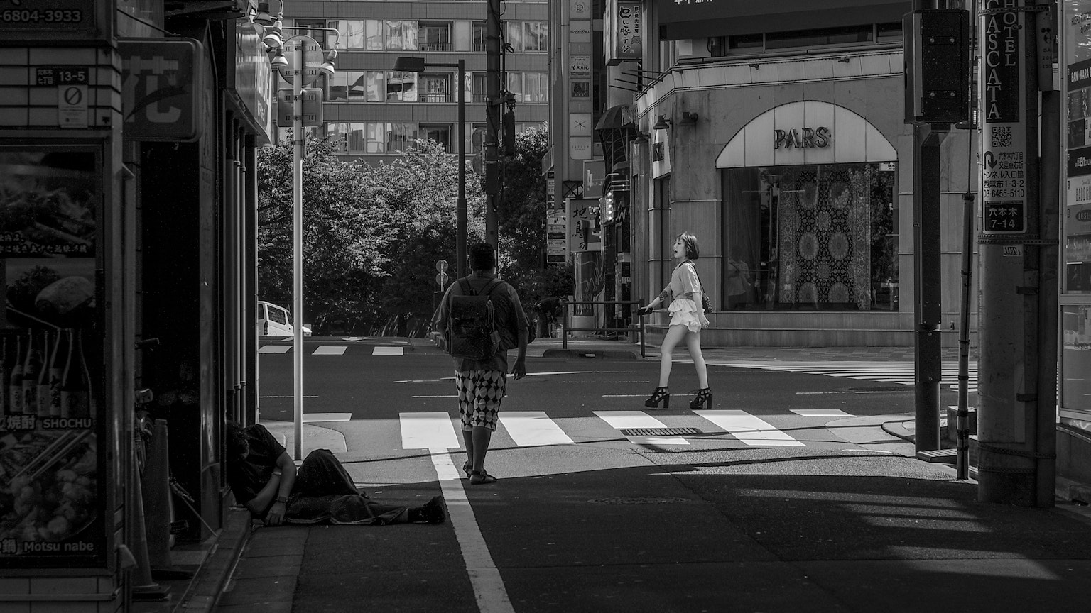 Escena de calle en blanco y negro con peatones cruzando y escaparates