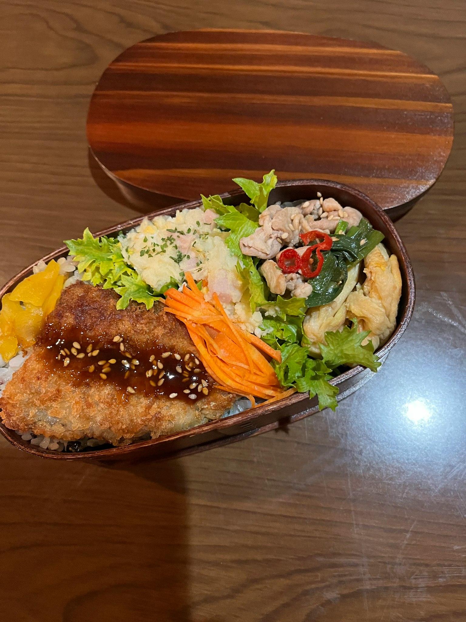 Eine schön arrangierte Bento-Box mit frittierten Speisen, Gemüse, Salat und weißem Reis