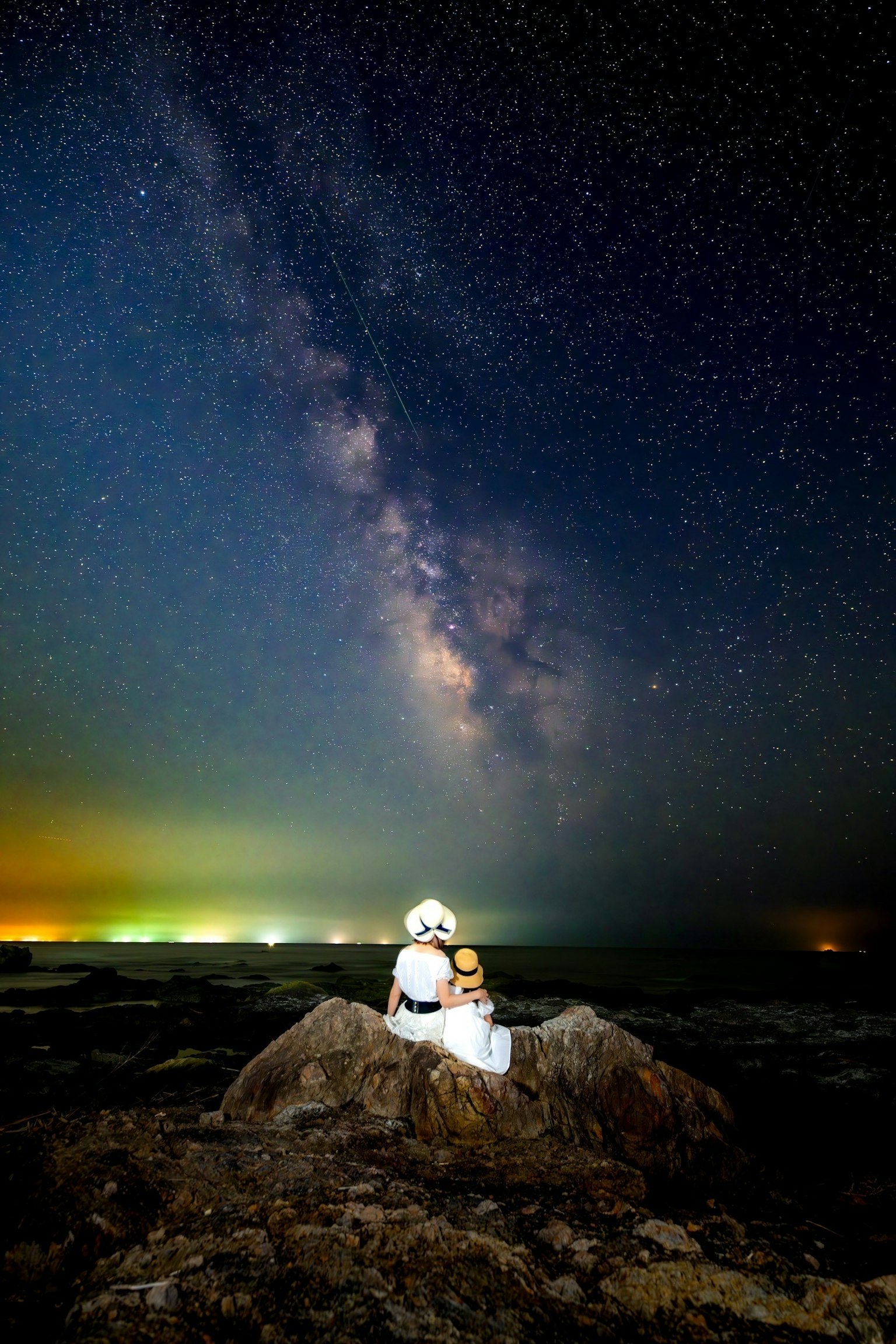 在星空下坐在岩石上的两个人物
