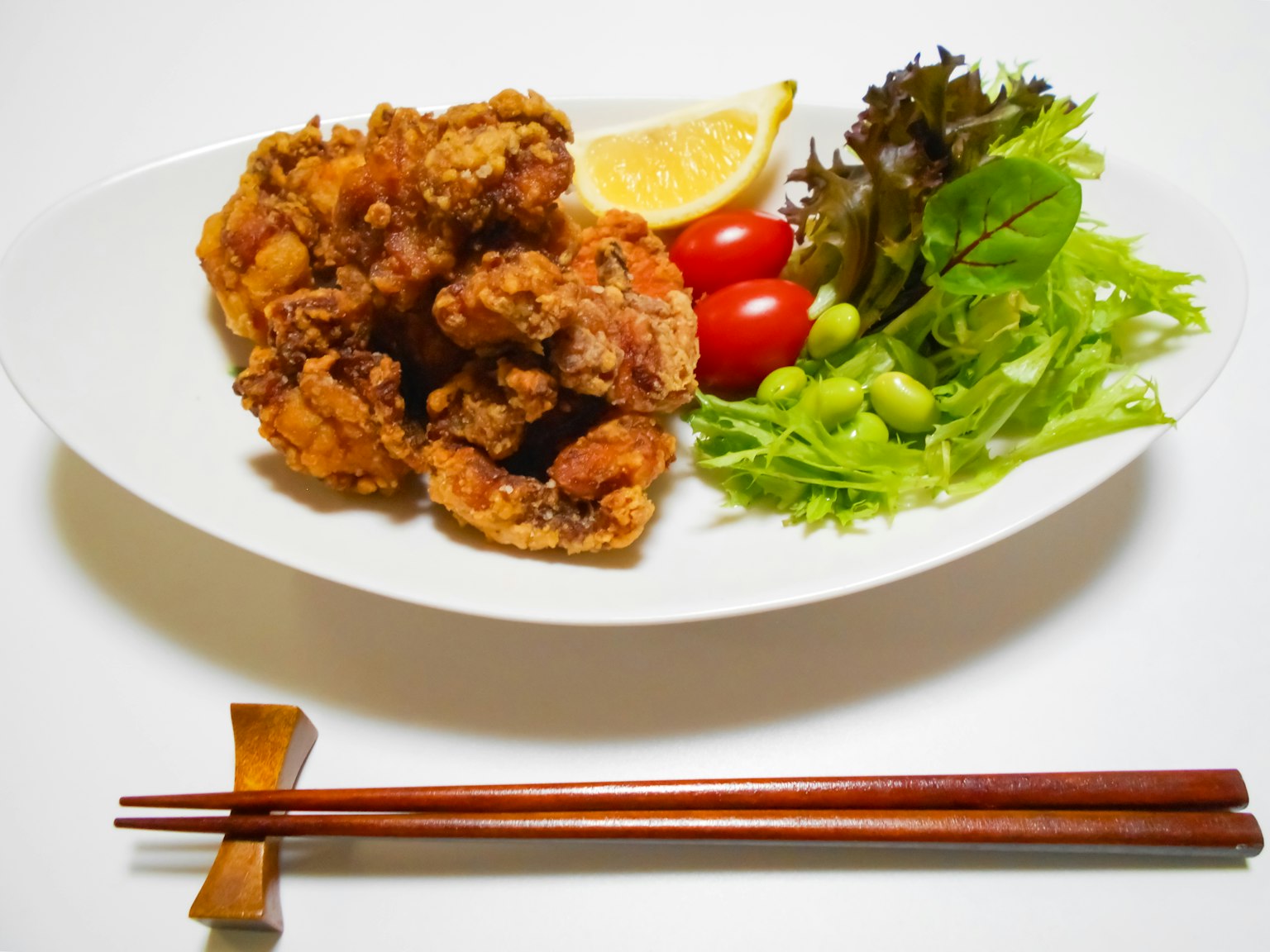 Đĩa gà chiên với chanh và salad được phục vụ với đũa
