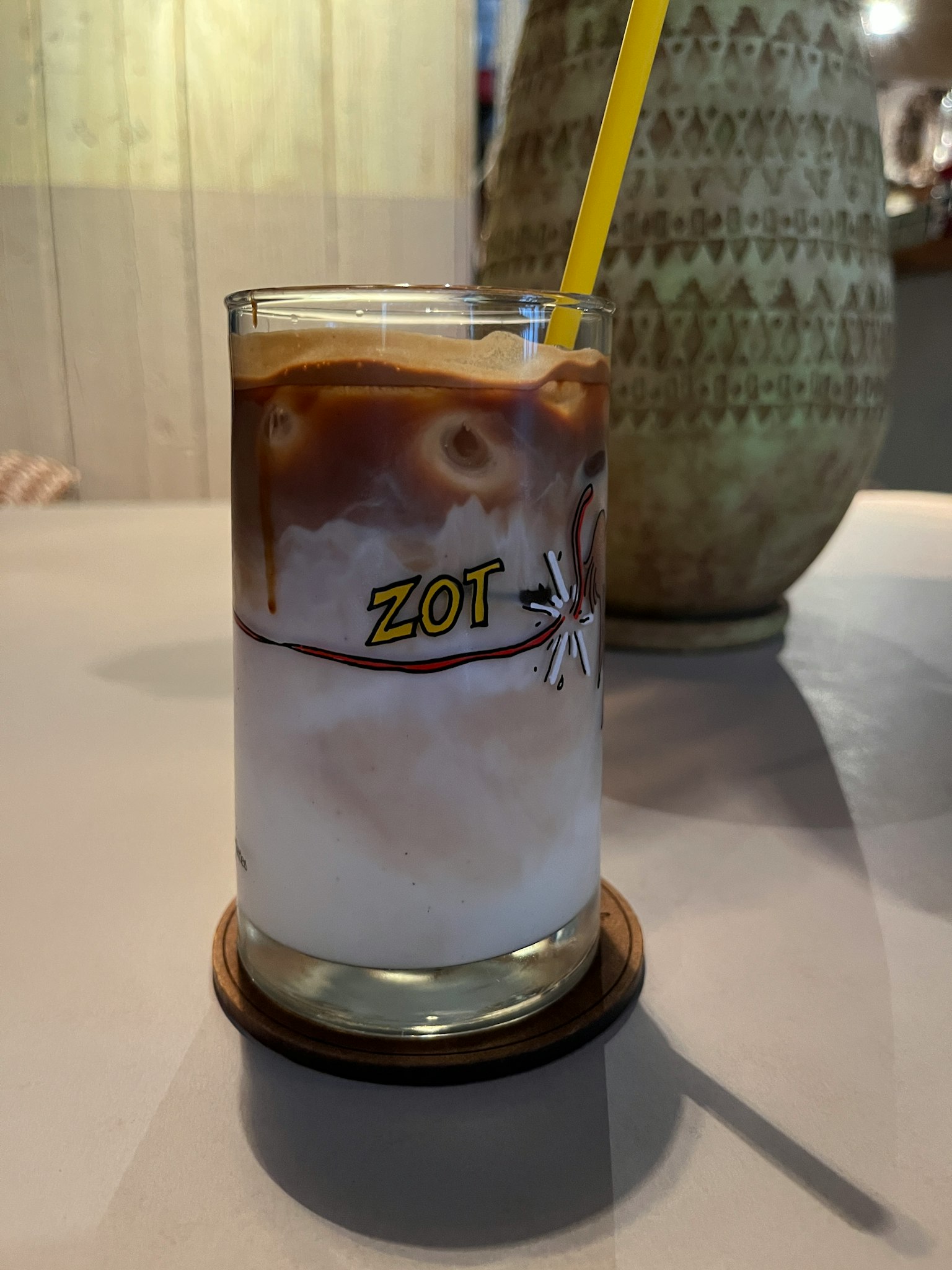 Un vaso de café helado con una pajilla amarilla sobre una mesa