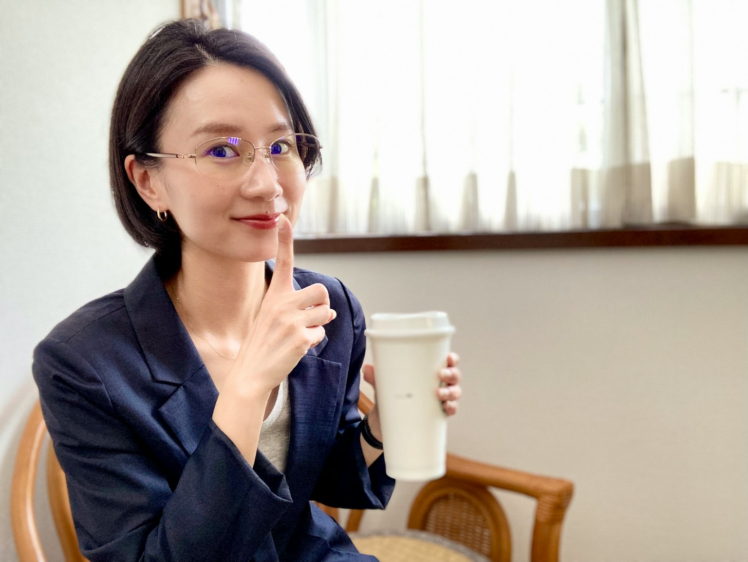 Donna che tiene una tazza di caffè con un dito sulle labbra in un gesto silenzioso