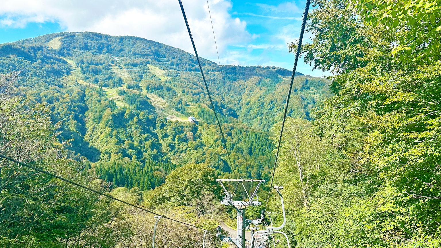 Vue panoramique depuis un téléphérique sur des montagnes verdoyantes et un ciel bleu