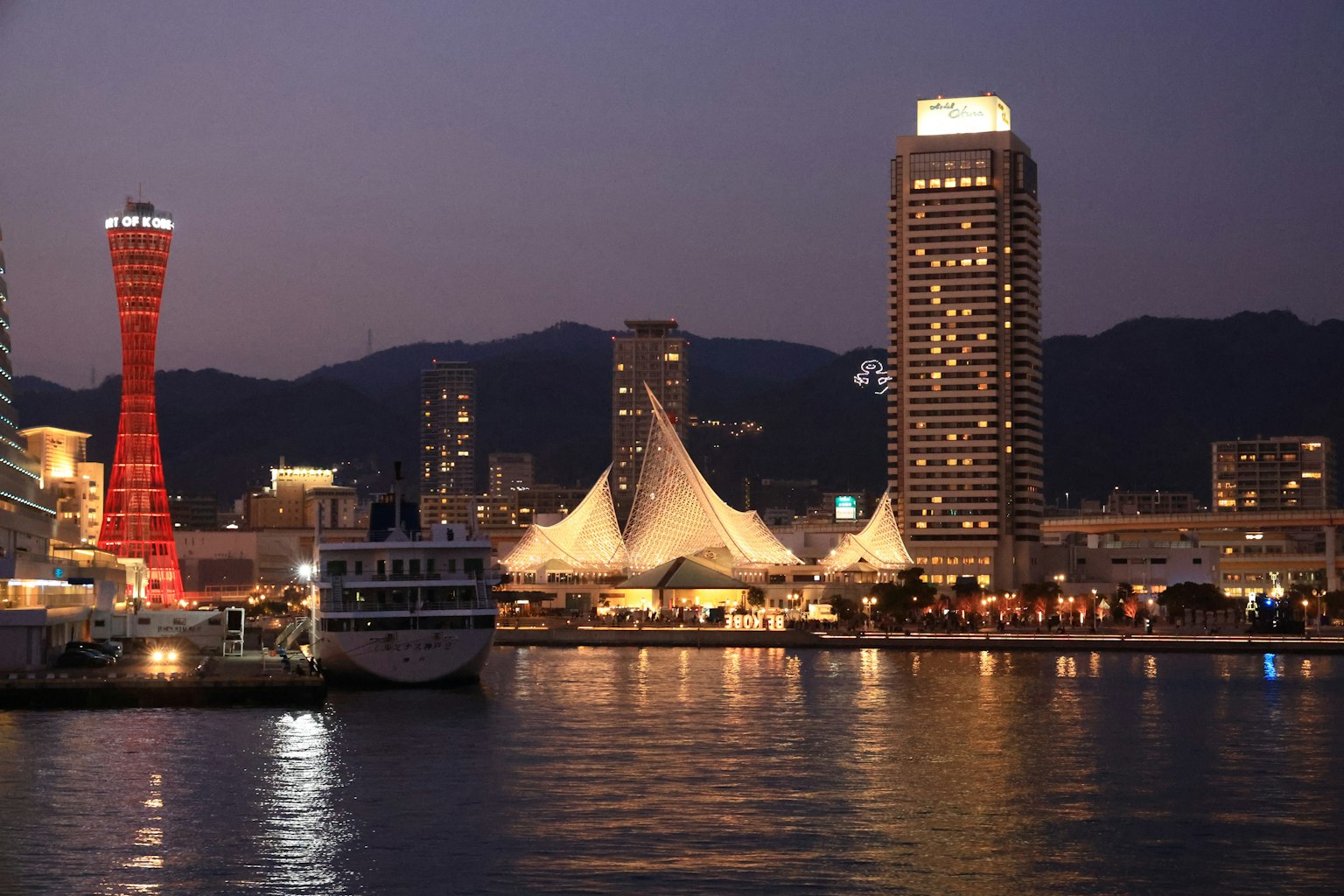 Vue nocturne du port de Kobe avec une tour rouge et des gratte-ciels modernes