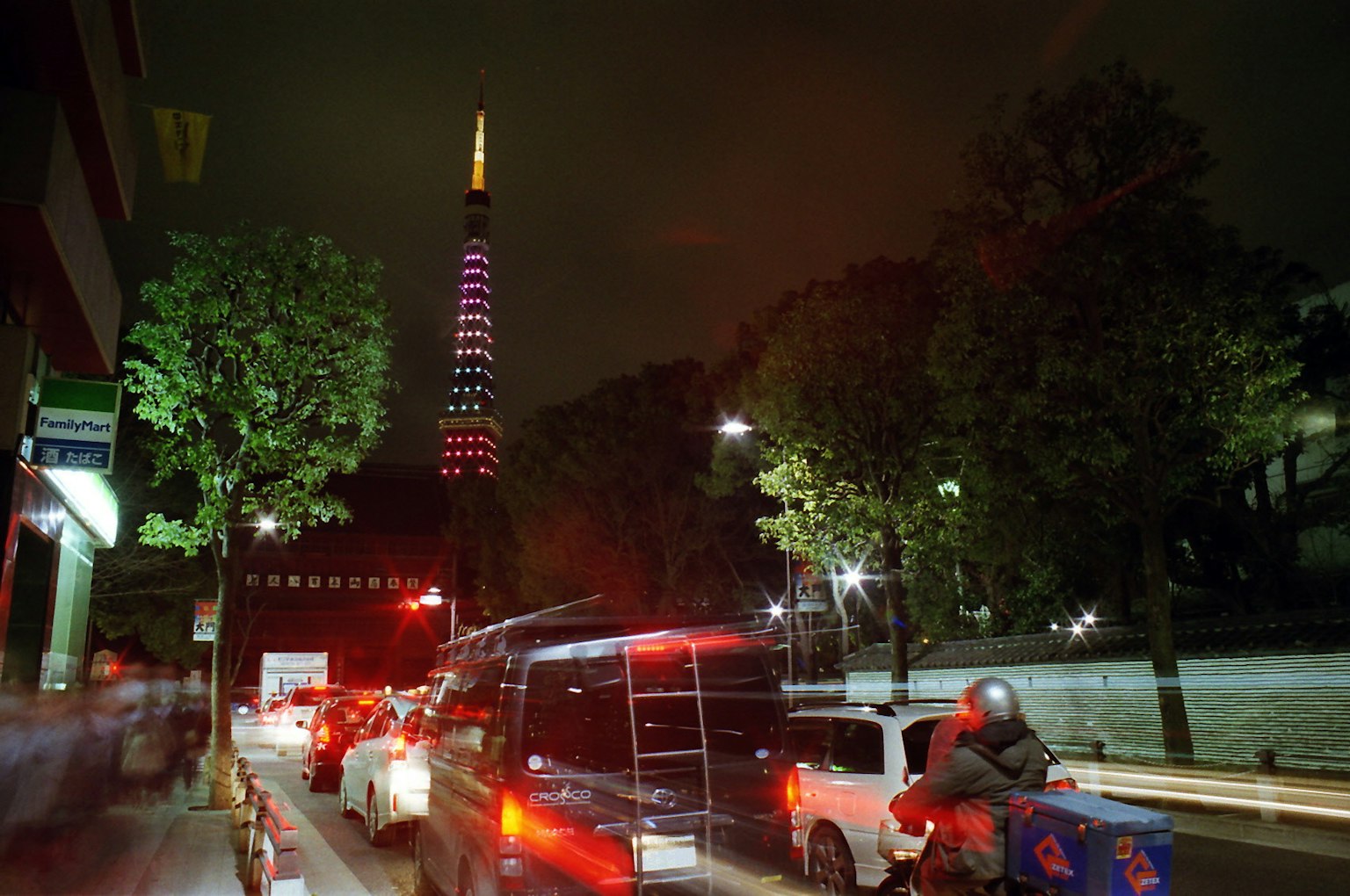 ทิวทัศน์ยามค่ำคืนของโตเกียวทาวเวอร์ที่ประดับด้วยไฟสีสันและการจราจรในพื้นหน้า