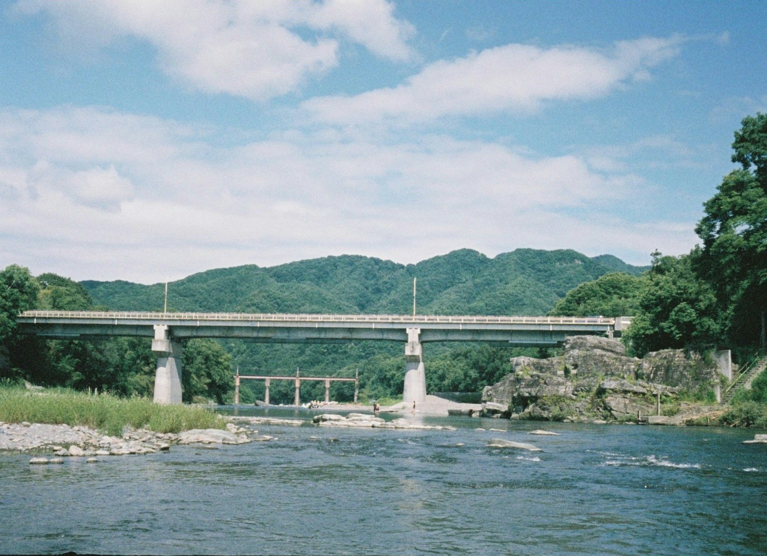 Vista panoramica di un ponte su un fiume con montagne verdi sullo sfondo sotto un cielo blu