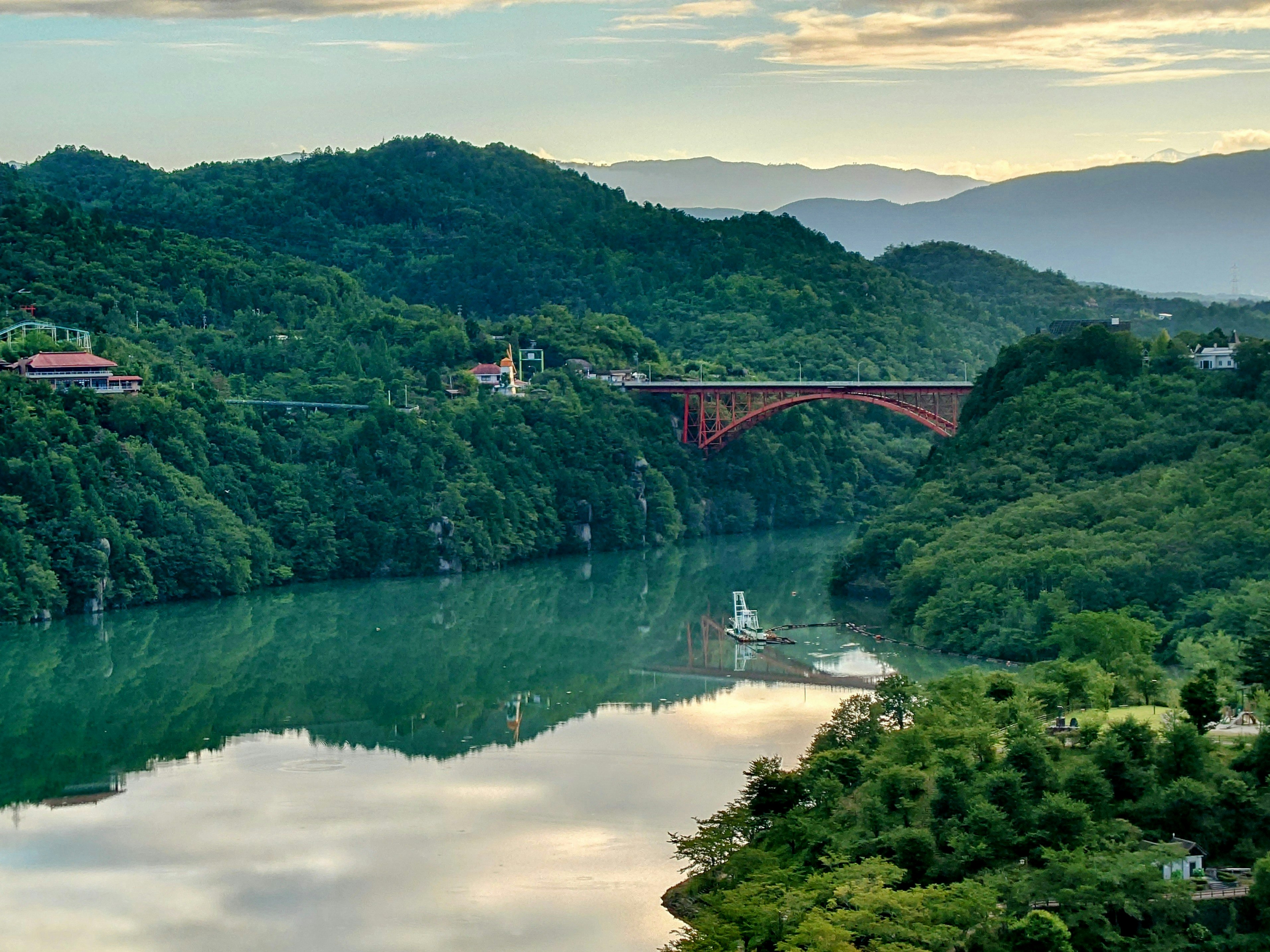 緑豊かな山々と川が流れる風景 赤い橋が川を横切る美しい景色