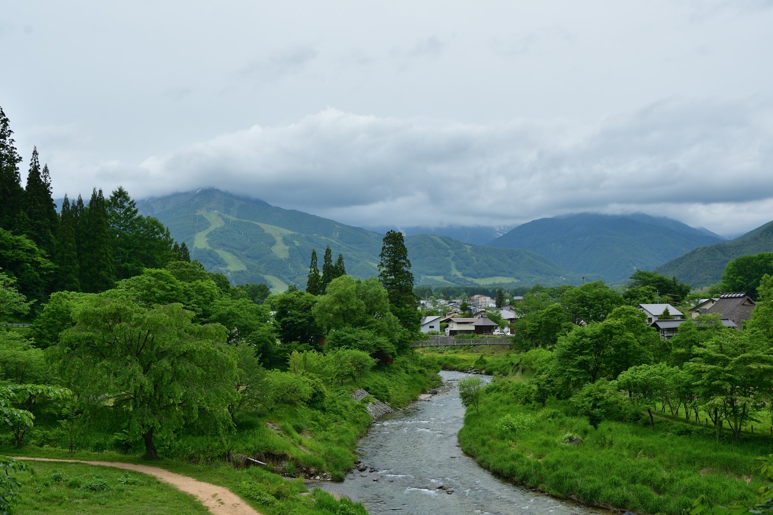 郁郁蔥蔥的山脈和流淌的河流，背景中有一個小村莊