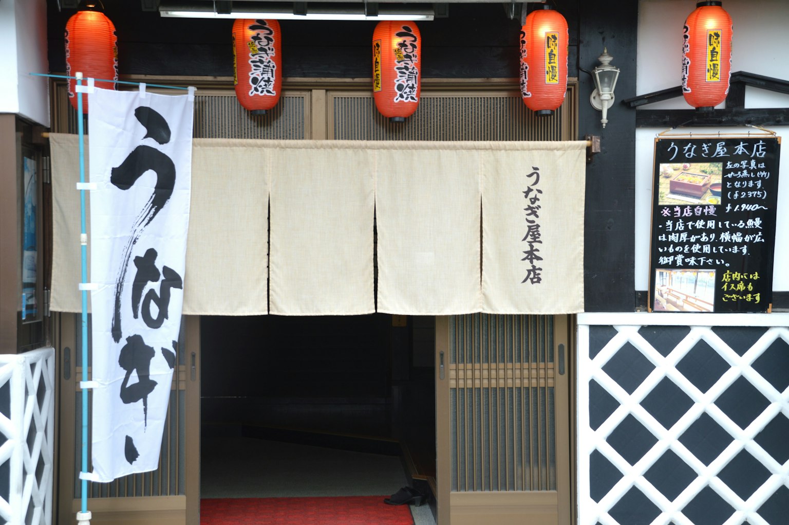 Entrada de un restaurante japonés tradicional con un noren blanco y faroles rojos
