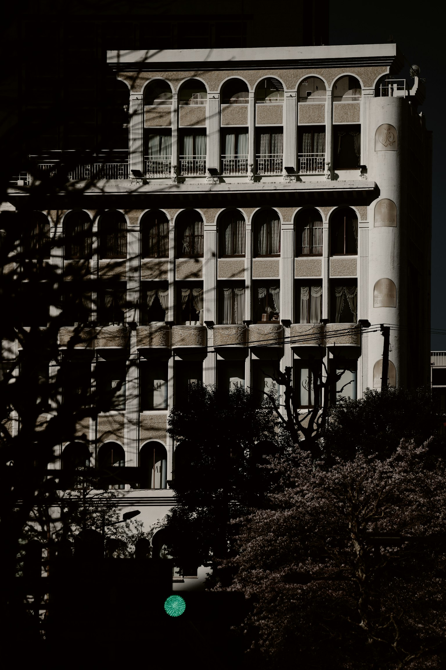 Vista laterale di un edificio bianco con finestre ad arco su uno sfondo scuro