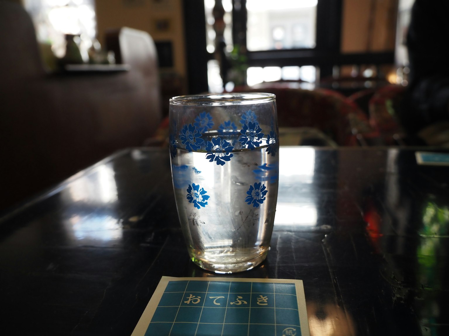Un bicchiere con motivi floreali blu riempito d'acqua su un tavolo da caffè