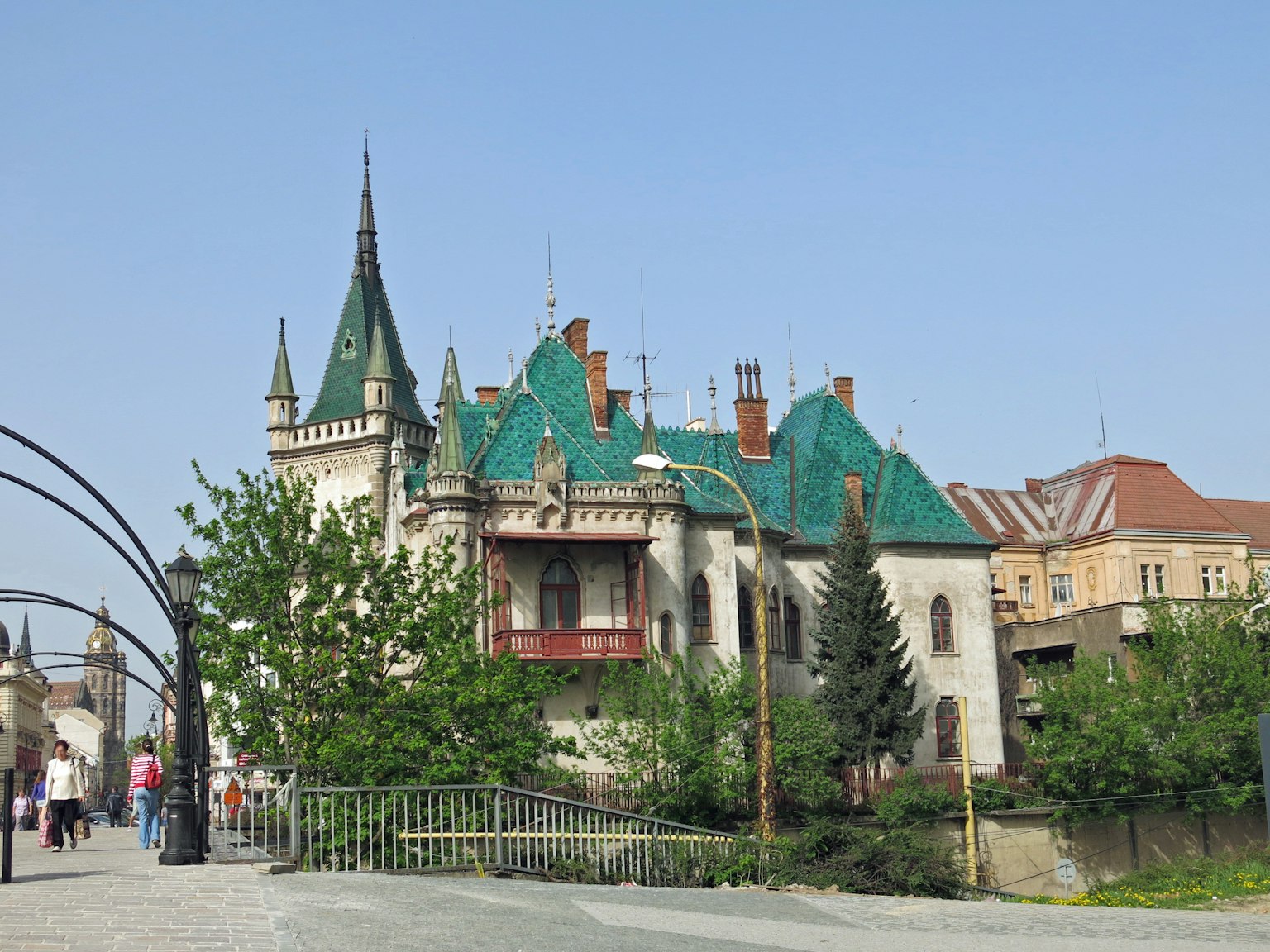 Un hermoso edificio parecido a un castillo con techos verdes y árboles alrededor