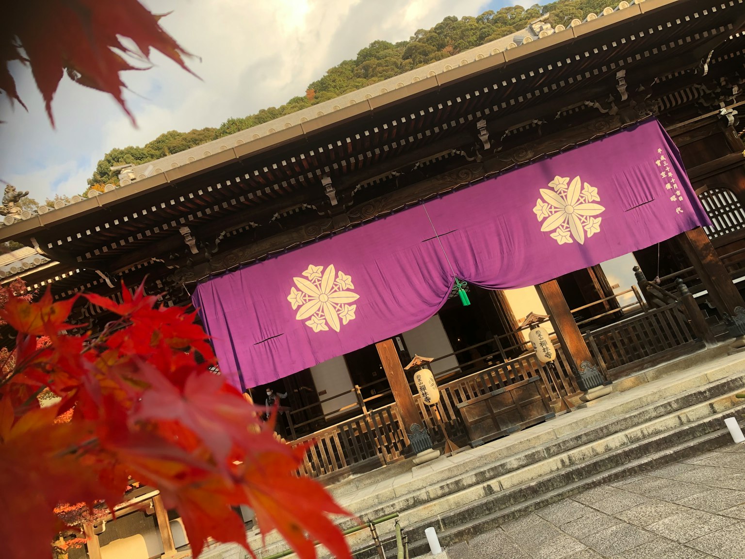Traditional building with purple fabric and floral symbols in front of vibrant autumn leaves