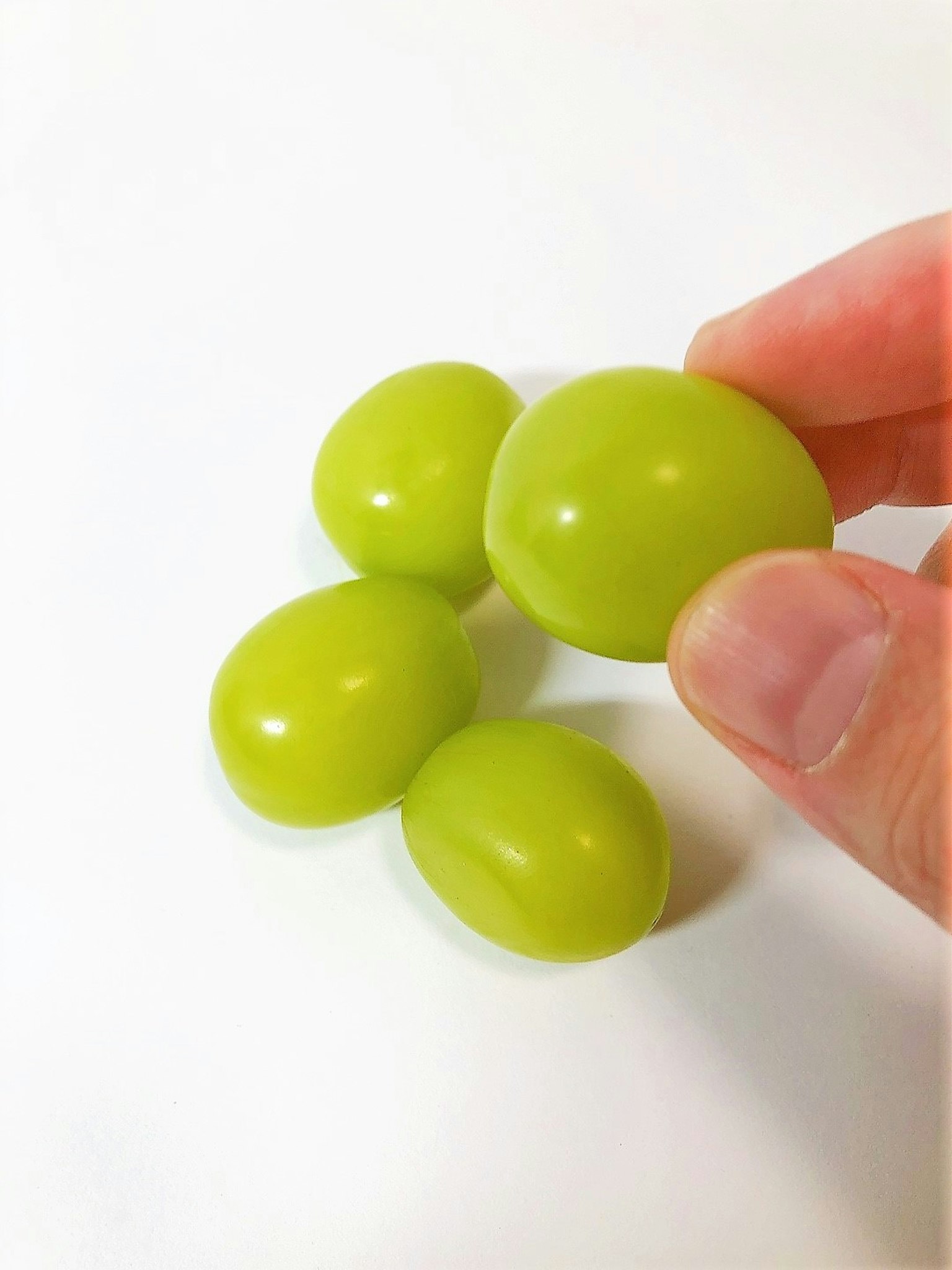 Imagen de uvas verdes sostenidas en una mano sobre un fondo blanco