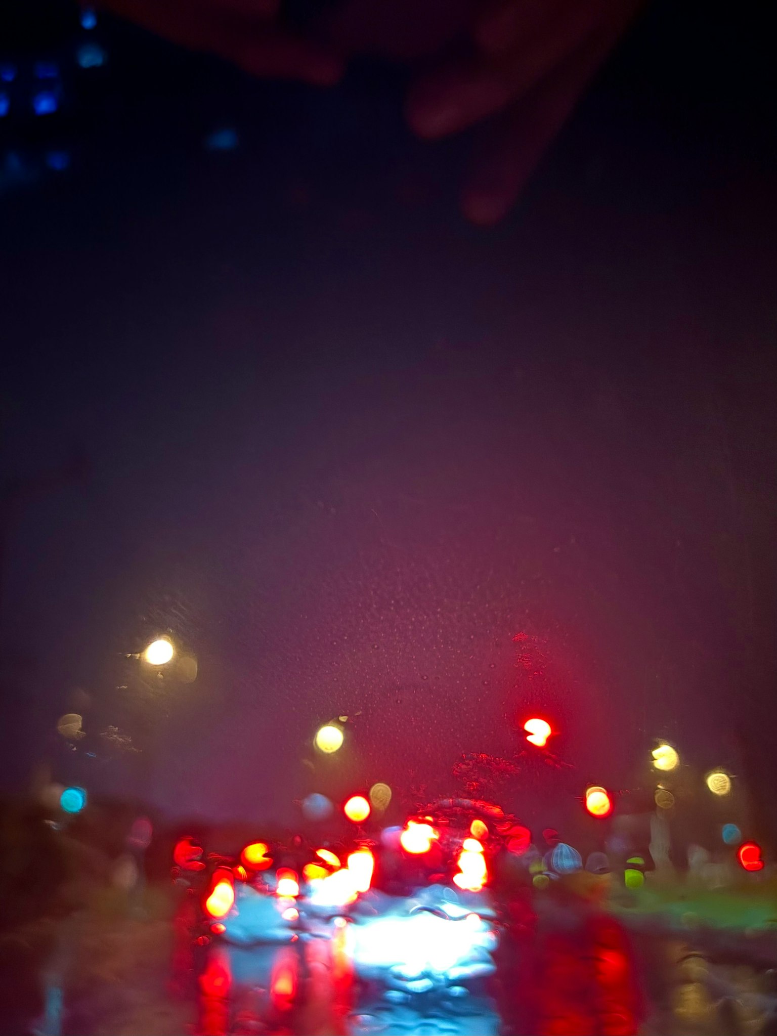 雨の中の車のテールライトと信号機の光がぼやけている夜の風景