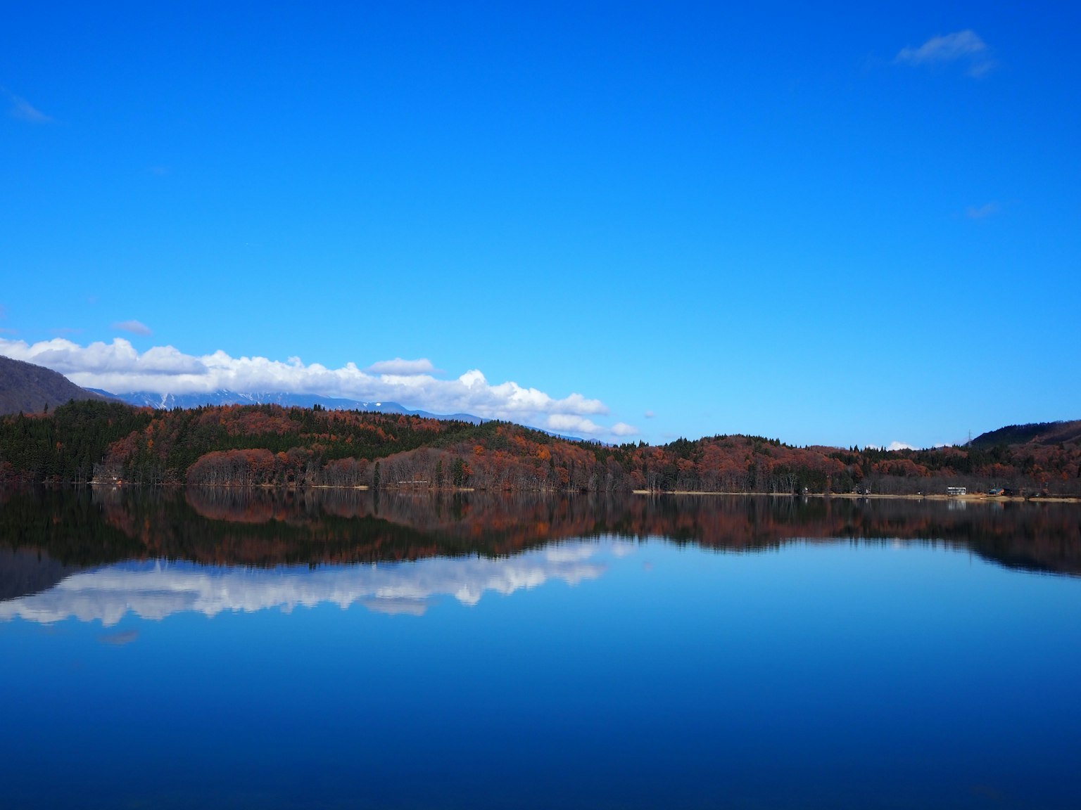A serene lake reflecting the blue sky and distant mountains