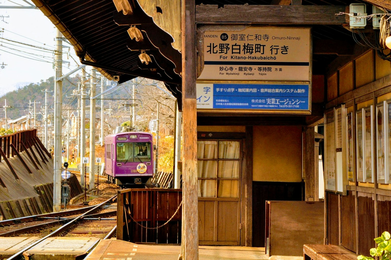 Un tren morado llegando a una estación de madera con un ambiente rústico