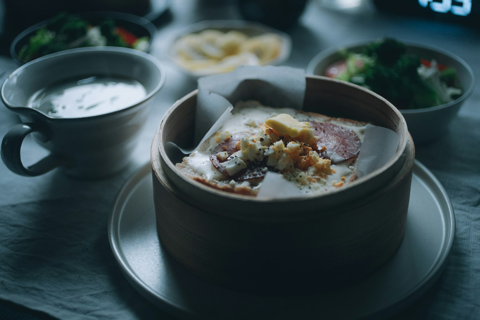 Món hấp trong xửng tre bao quanh bởi bát súp và salad