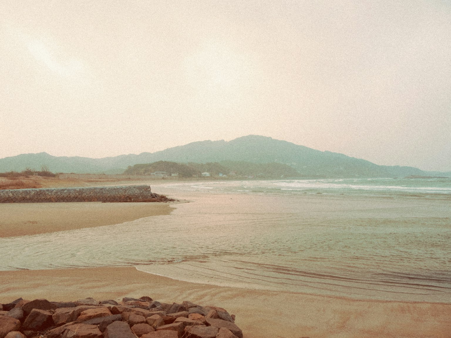 Vue de plage sereine avec des vagues douces et des montagnes lointaines