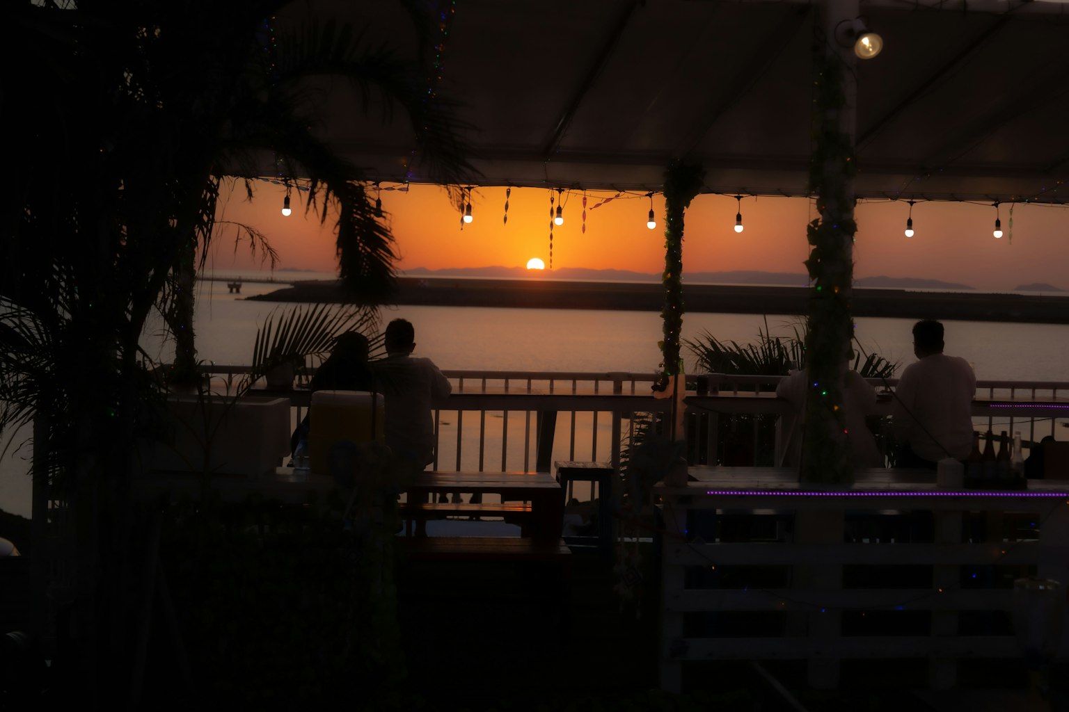 Magnifique coucher de soleil sur la mer avec des gens sur une terrasse