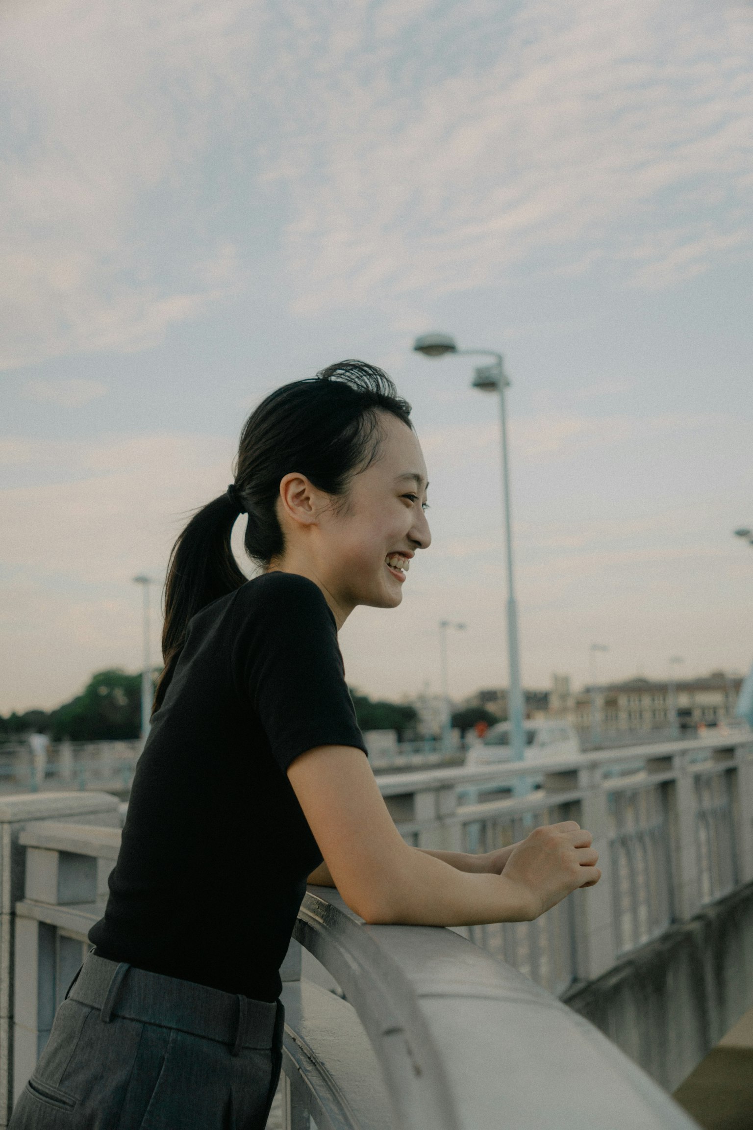 Profilo laterale di una donna sorridente su un ponte con cielo blu