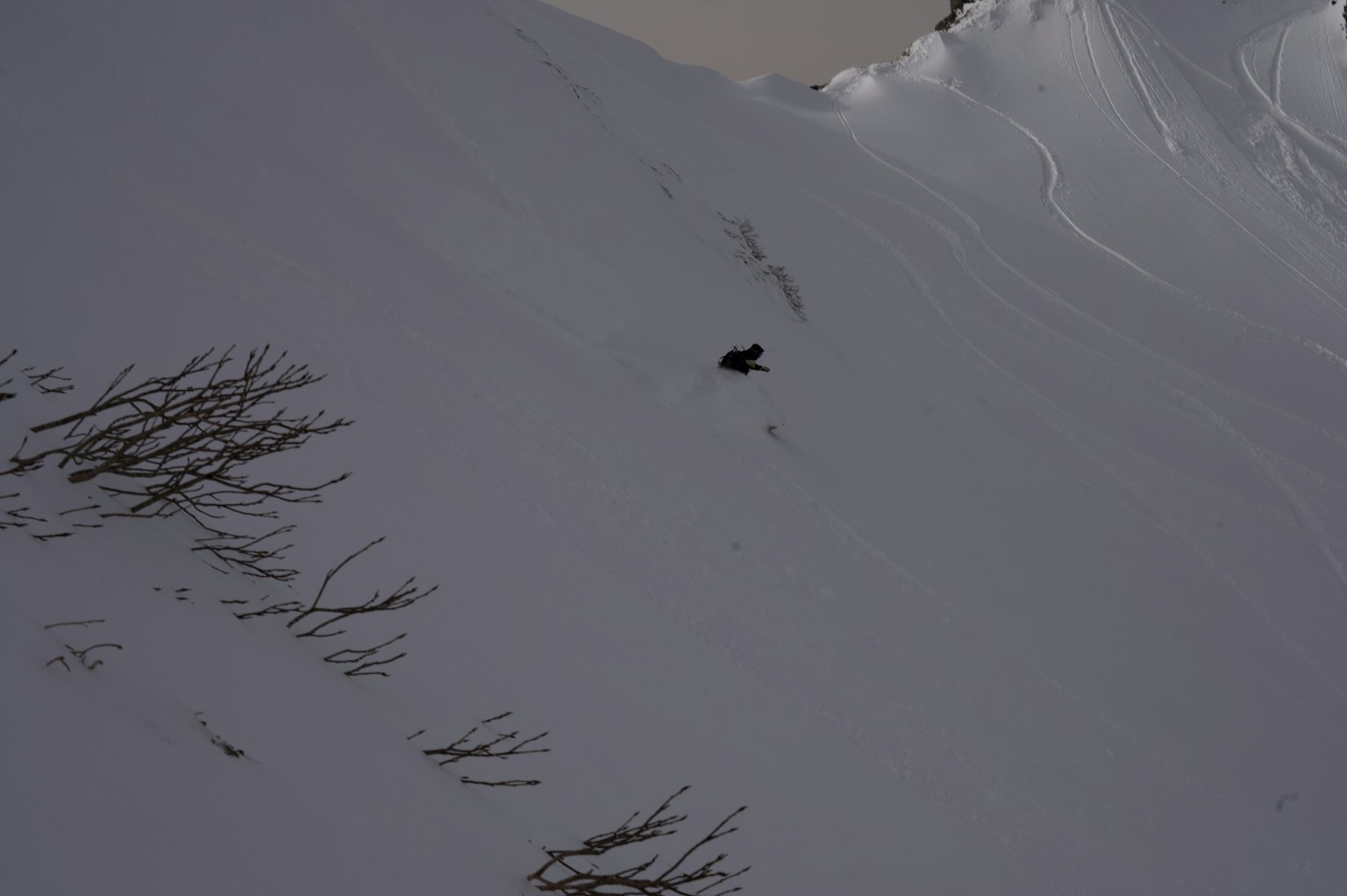 Silhouette d'un snowboarder descendant une pente enneigée
