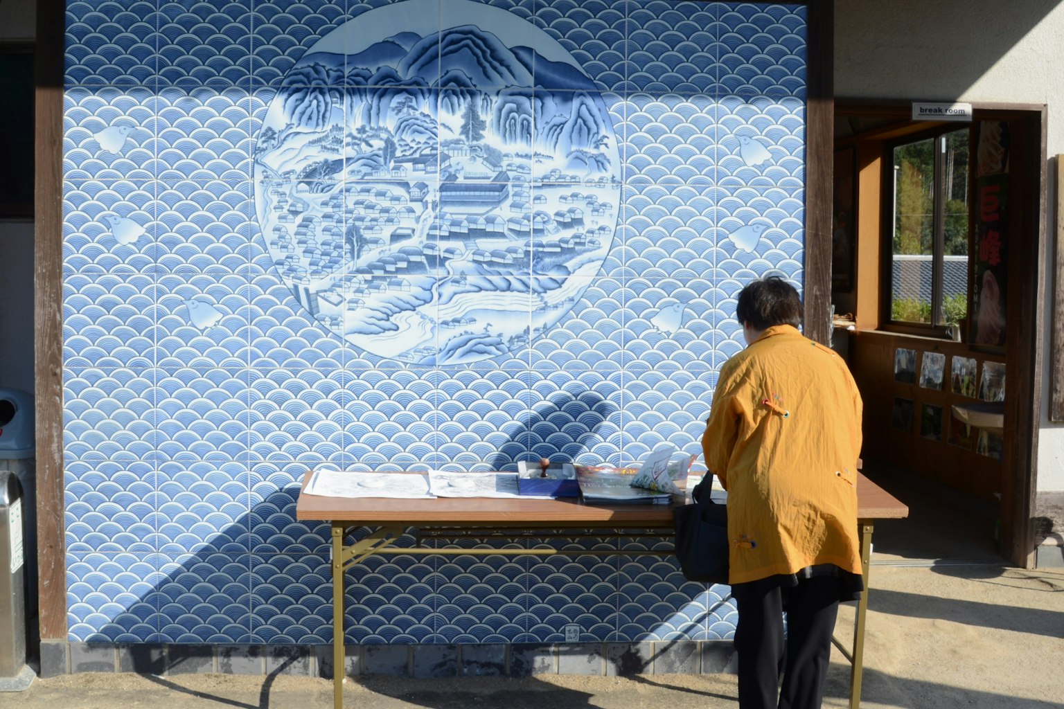 Person arbeitet an einem Tisch vor einem blauen Wandgemälde