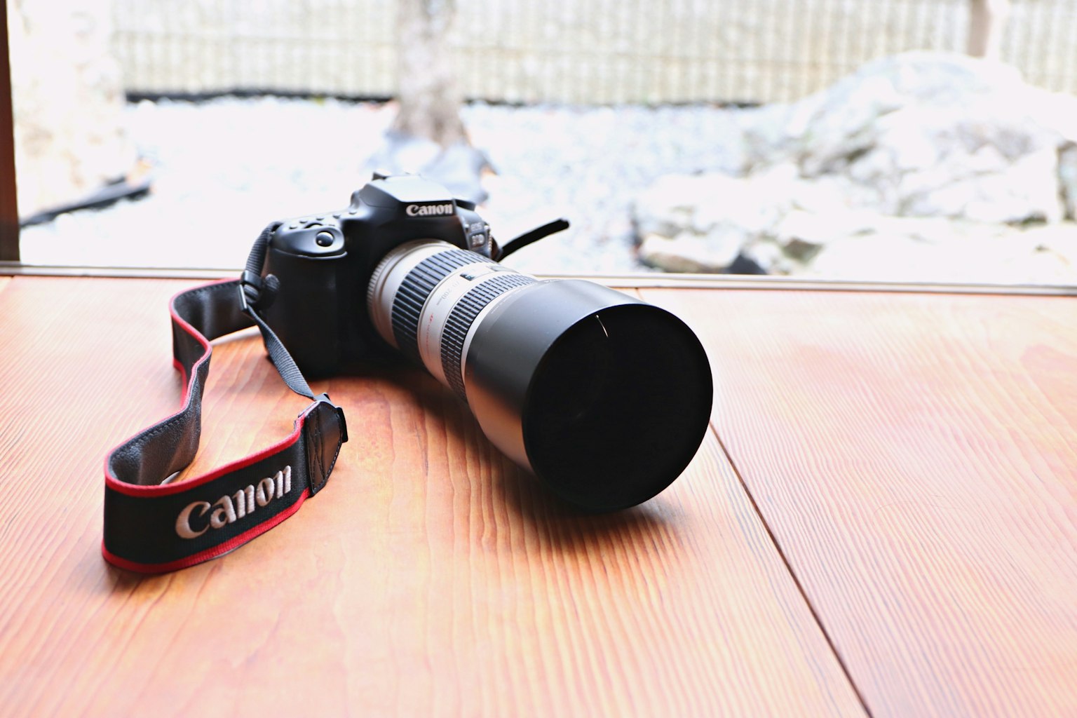 Una cámara Canon con un objetivo sobre una mesa de madera