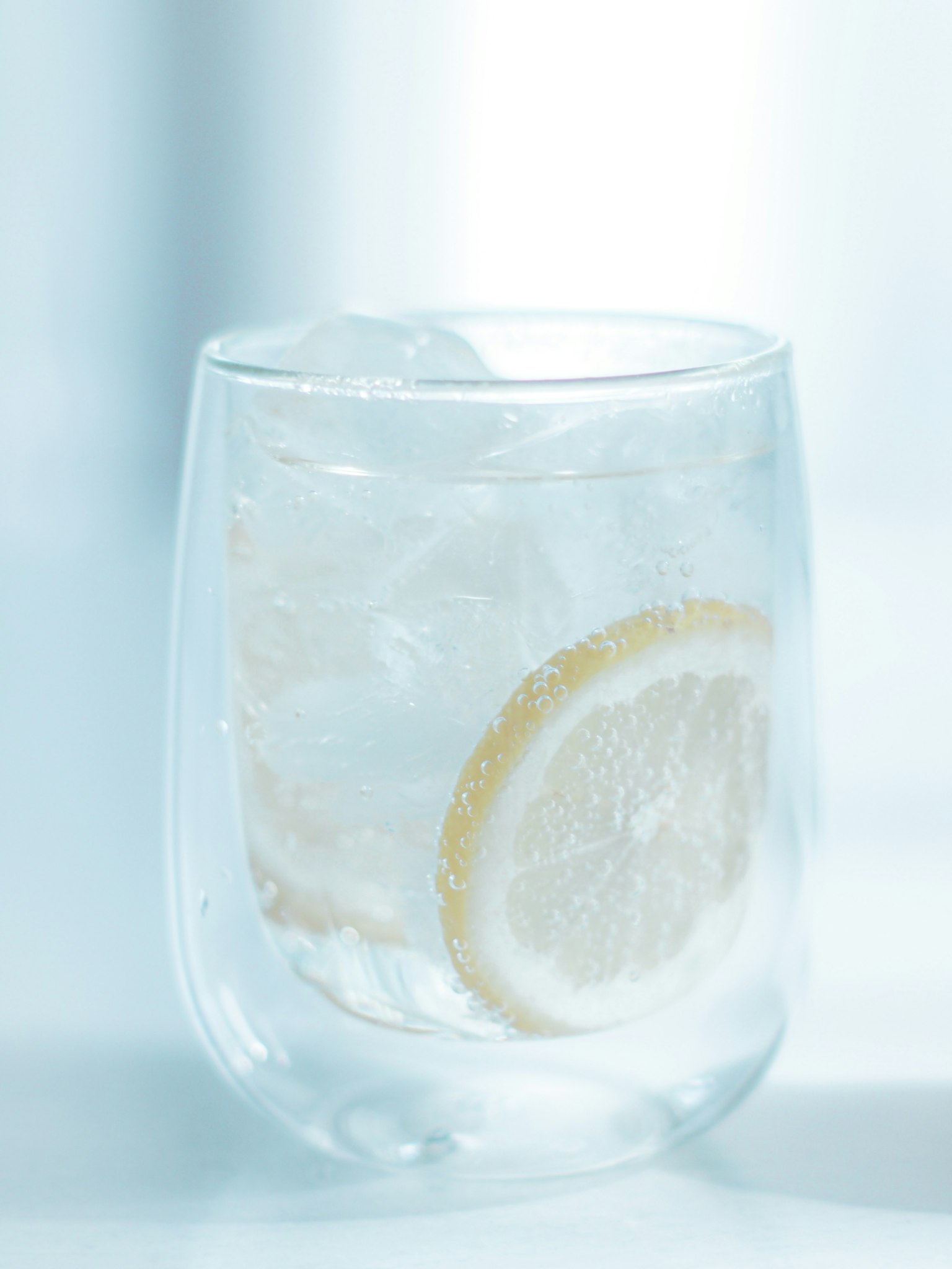 Transparent glass of water with ice and a slice of lemon