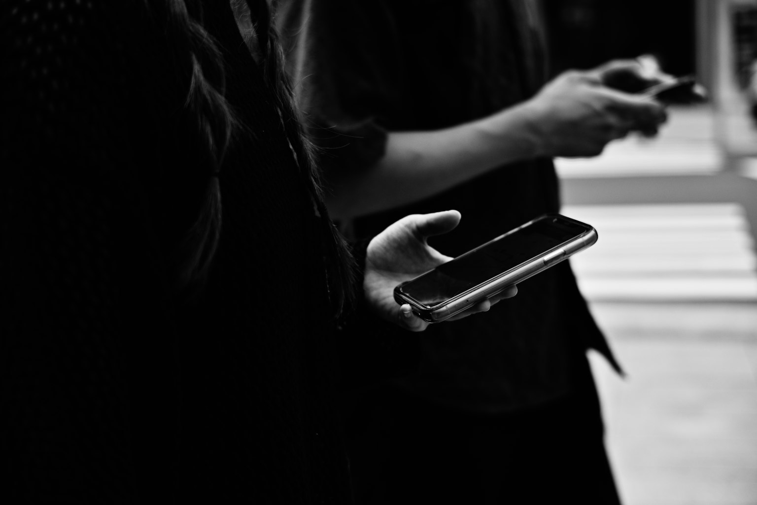 Close-up of hands holding smartphones against a dark background