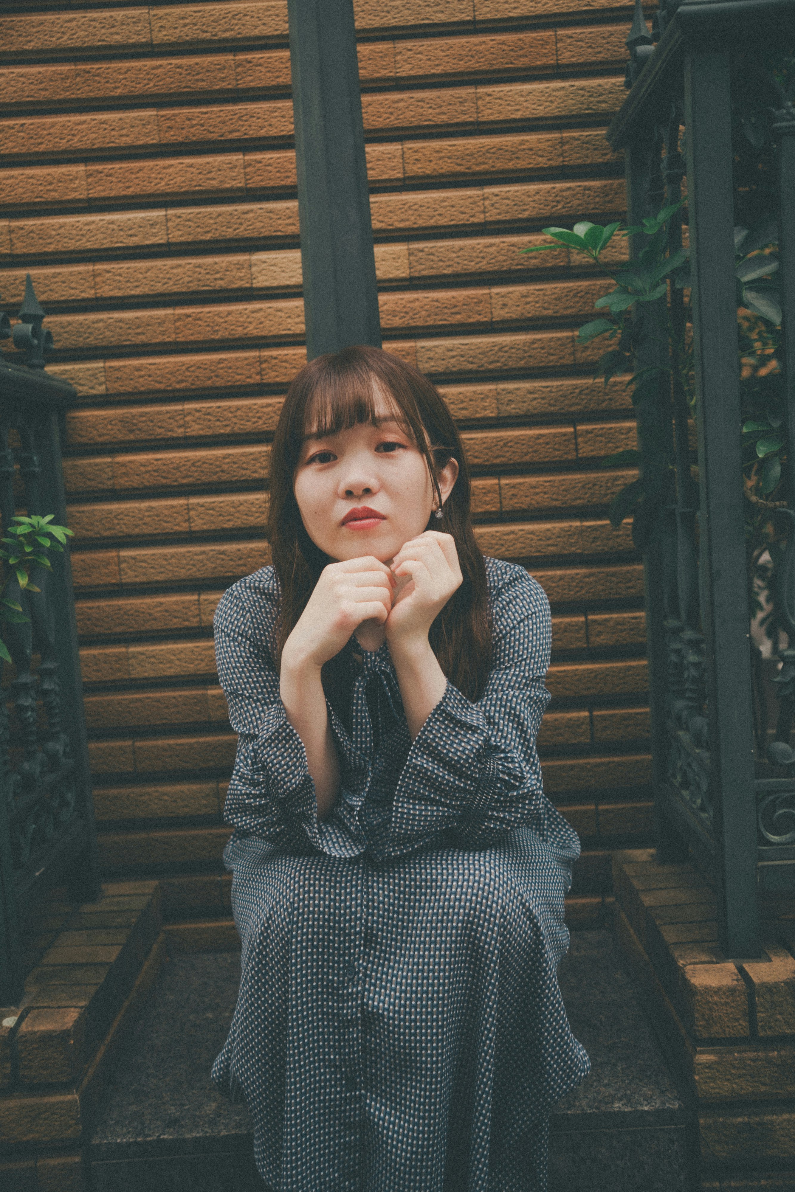 người phụ nữ tạo dáng với hai tay đặt lên má trước bức tường gỗ