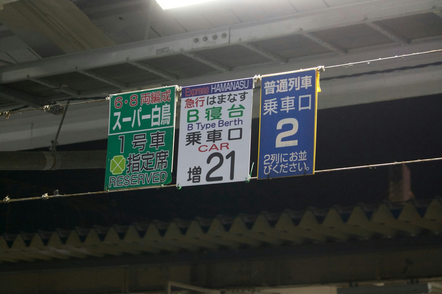 Station signage displaying supermarket directions and exit numbers