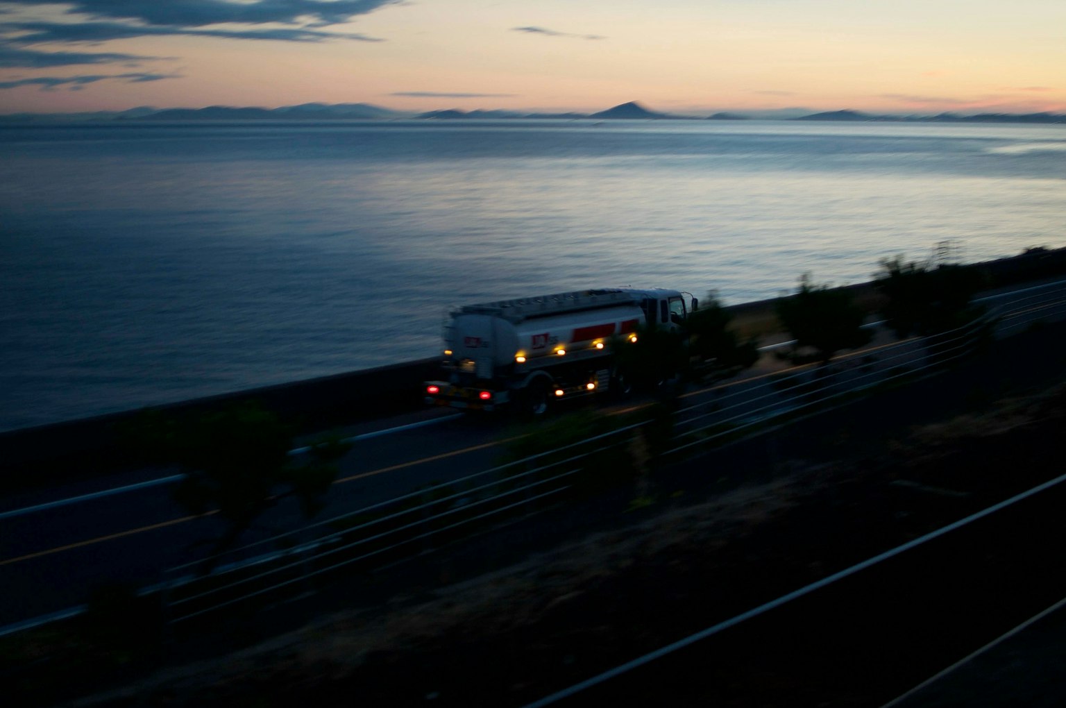 Bus driving along a coastal road at dusk