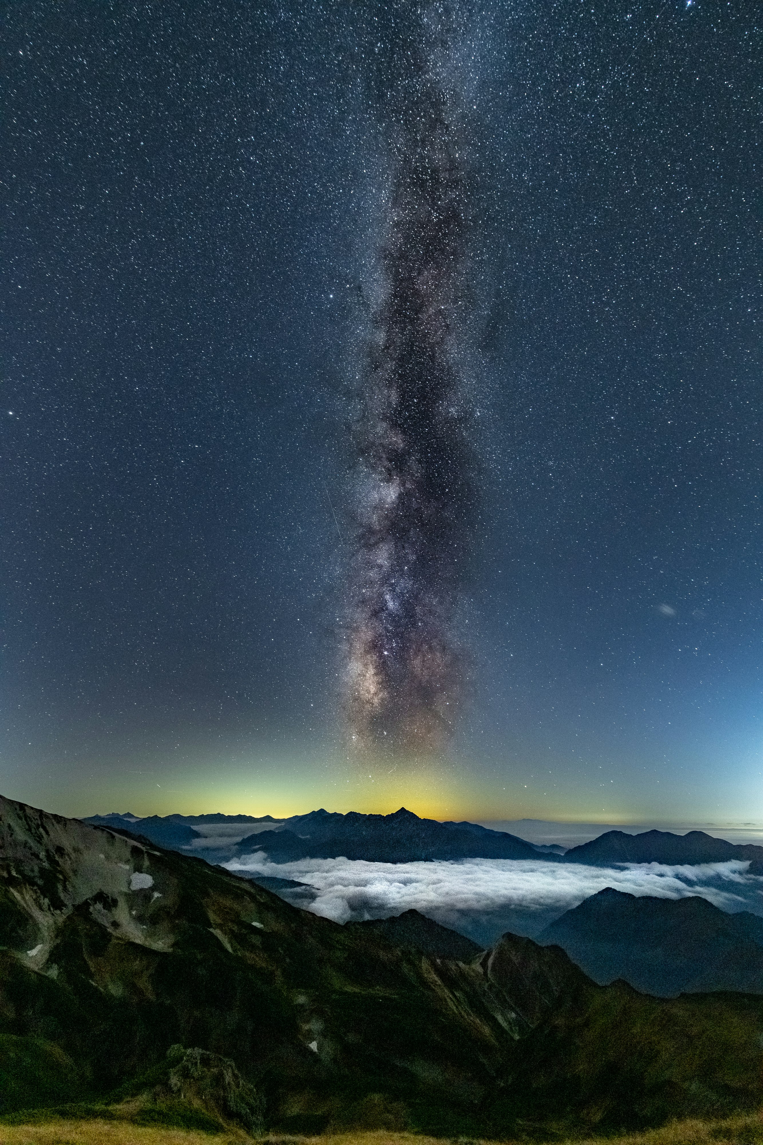 雲海の上にそびえる山並みと天の川の夜空