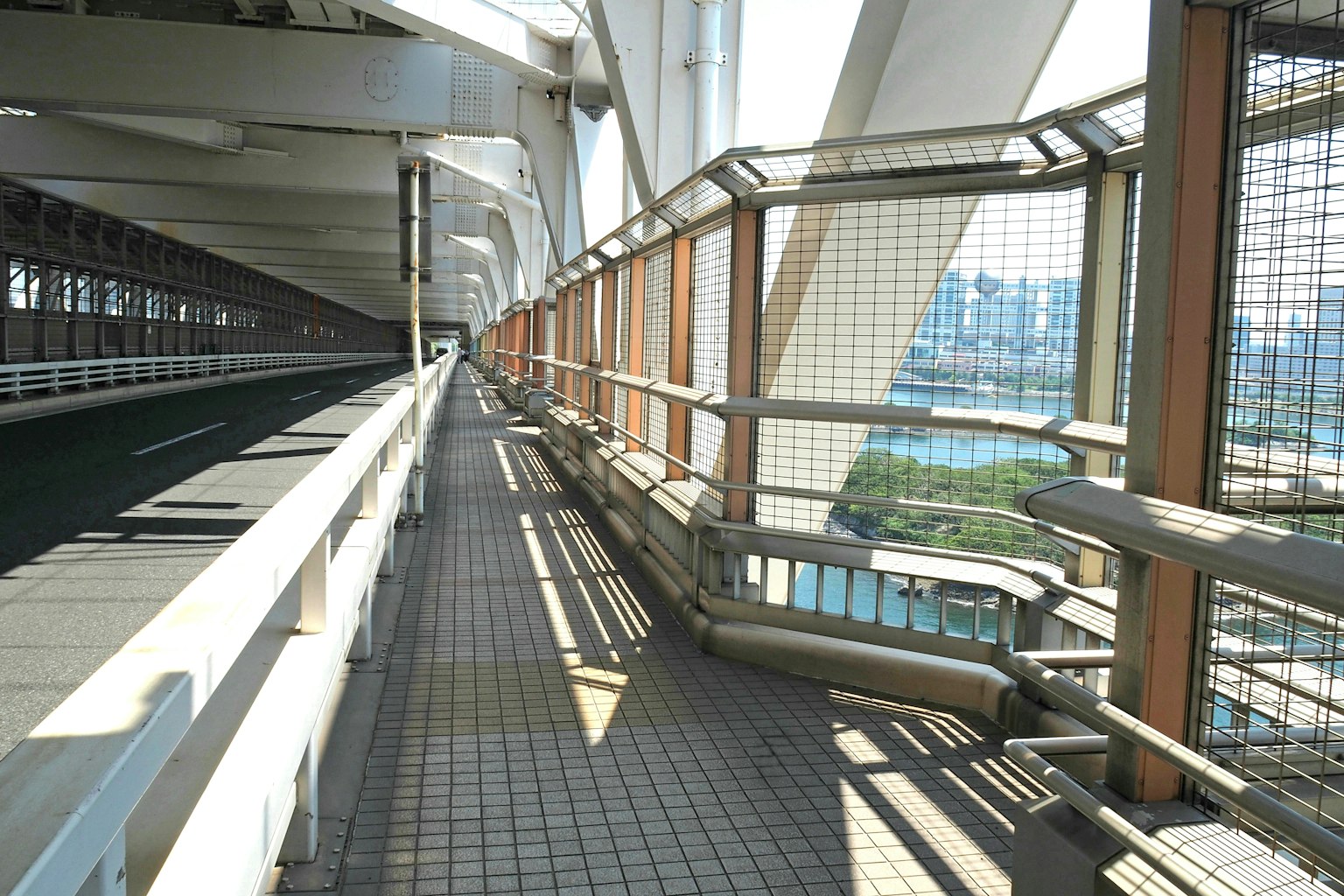 Perspektive eines Gehwegs auf einer Brücke mit strukturellen Elementen und hellem Sonnenlicht